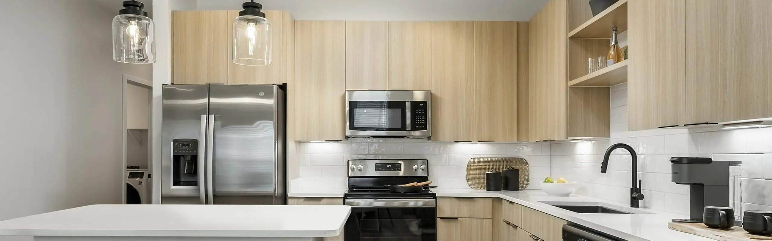 Modern kitchen with sleek stainless steel appliances, elegant pendant lighting, and a stylish island with seating for two.