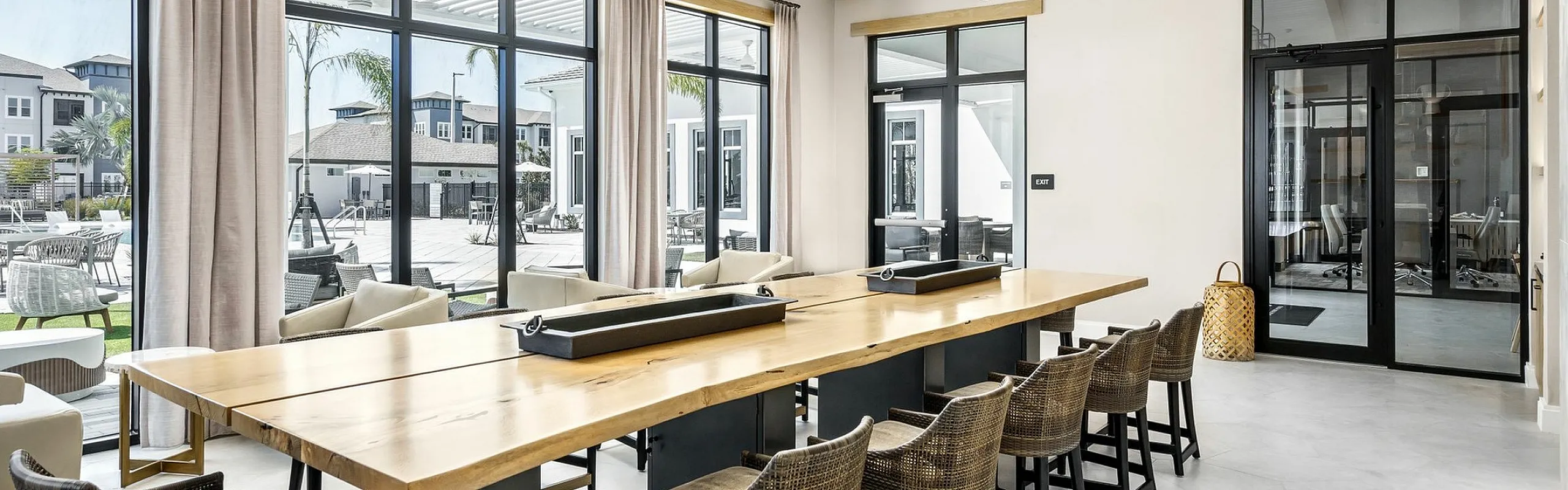 Elegant dining area with a long wooden table, modern chairs, and large windows offering a bright, inviting atmosphere.