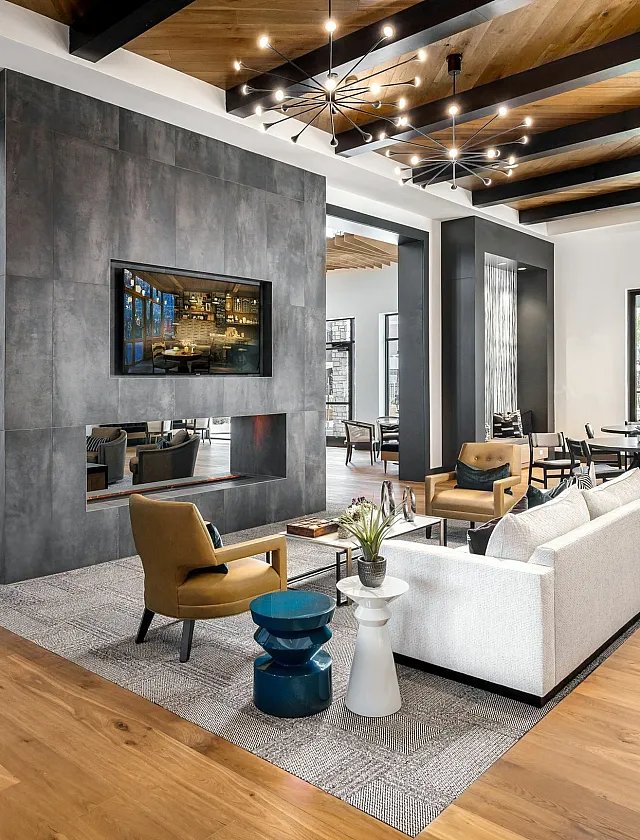 Luxurious open-concept living area with modern decor, featuring stylish seating, floor-to-ceiling windows, and a sleek central fireplace.