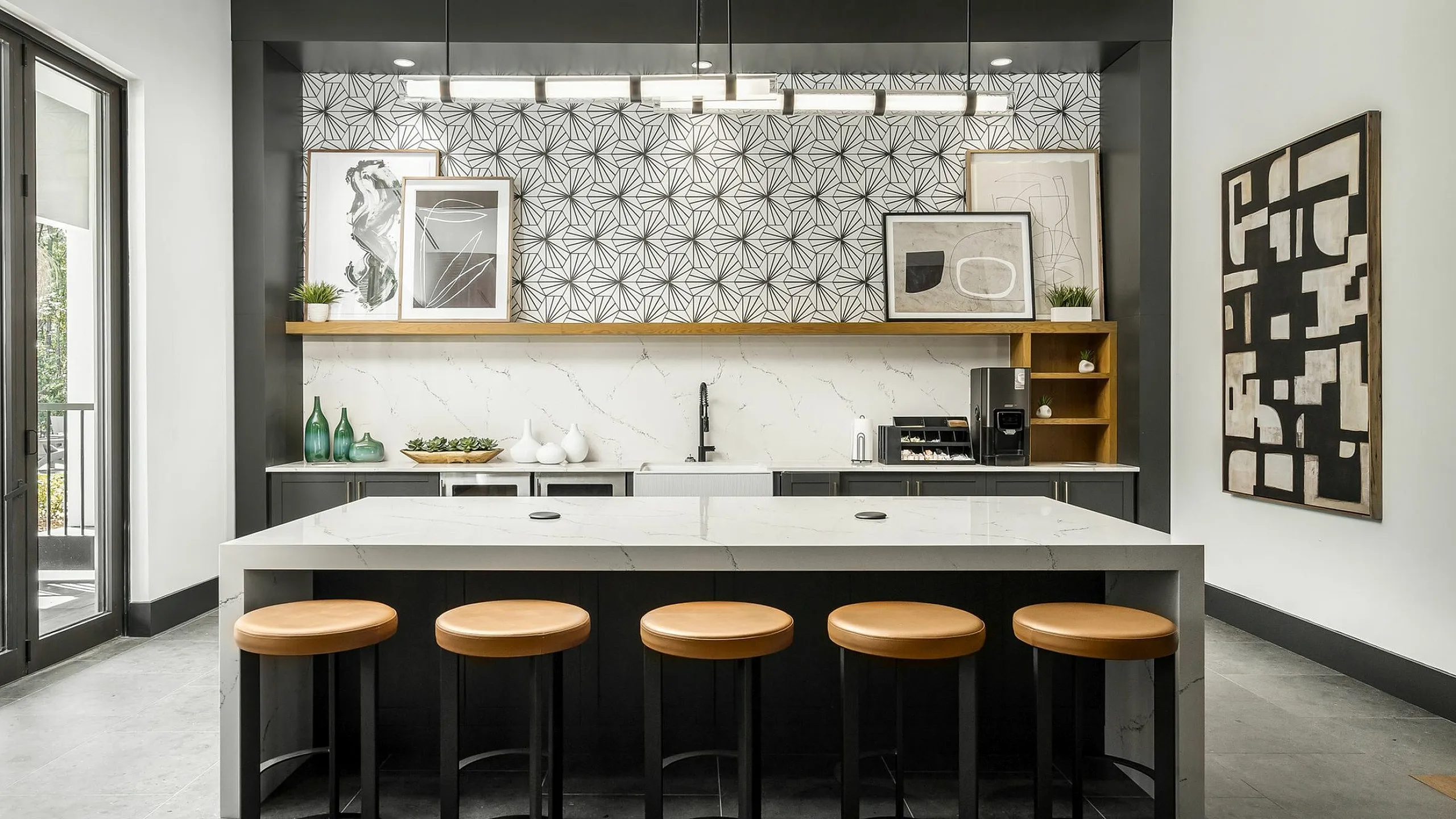 Chic modern kitchen with sleek island seating, artistic tile backsplash, and elegant lighting.