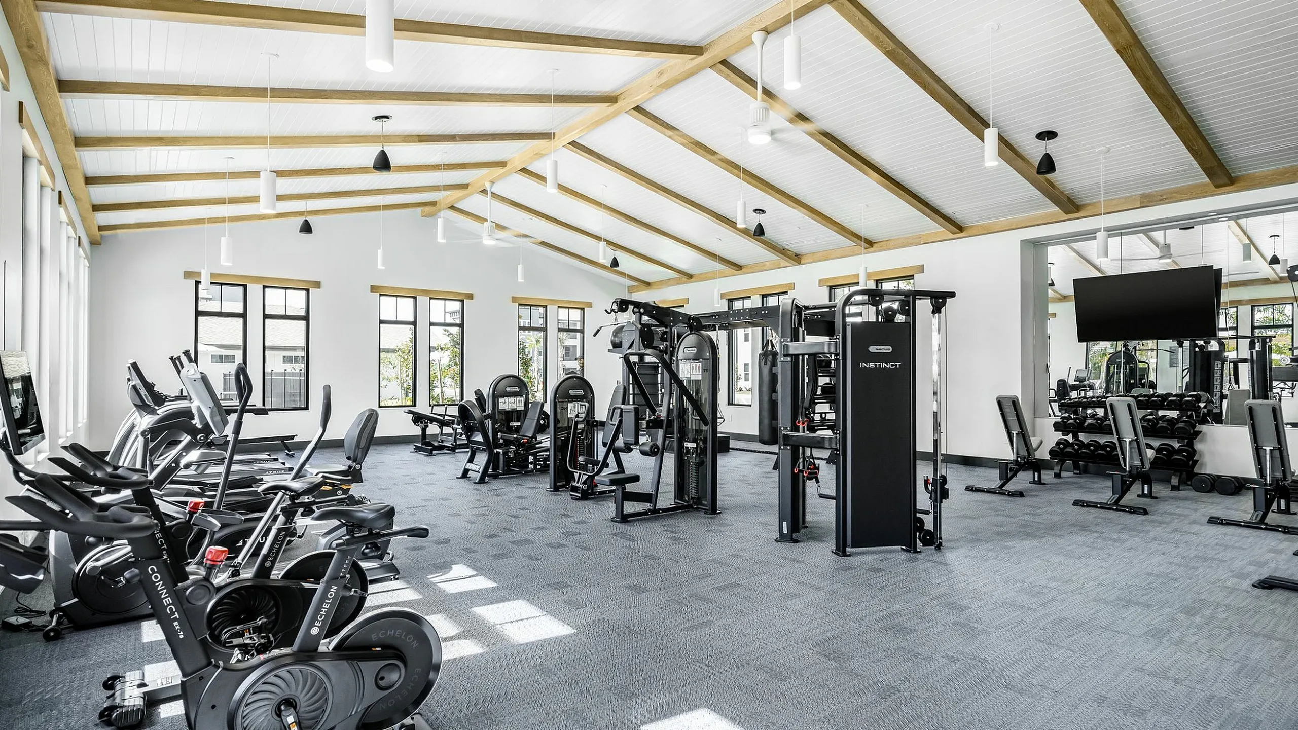 Spacious, modern fitness center featuring state-of-the-art exercise equipment and natural lighting through large windows.