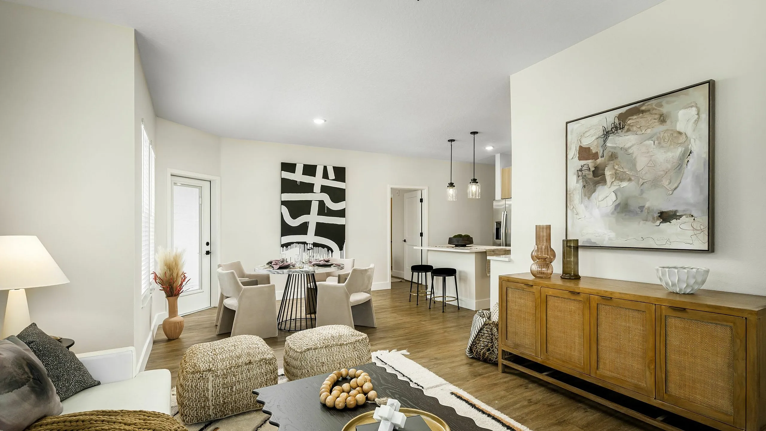 Modern open-concept living room with stylish decor, featuring a cozy seating area, elegant dining setup, and chic kitchen bar.