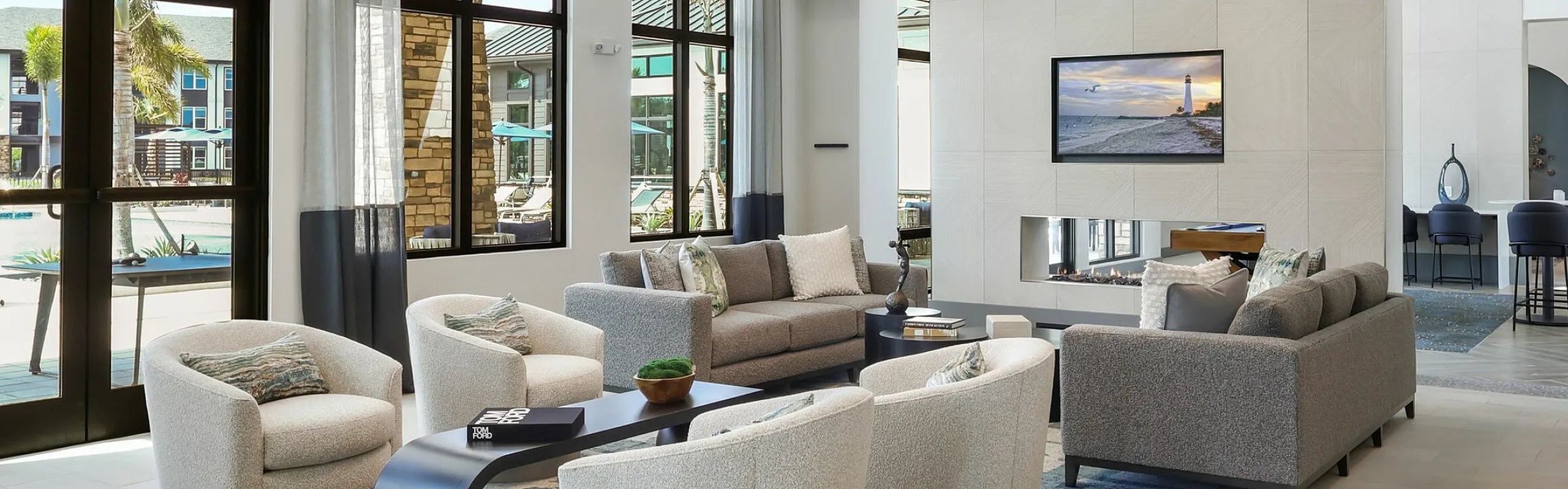 Modern and inviting living space with sleek furniture, ambient lighting, and large windows offering a view of palm trees outside.