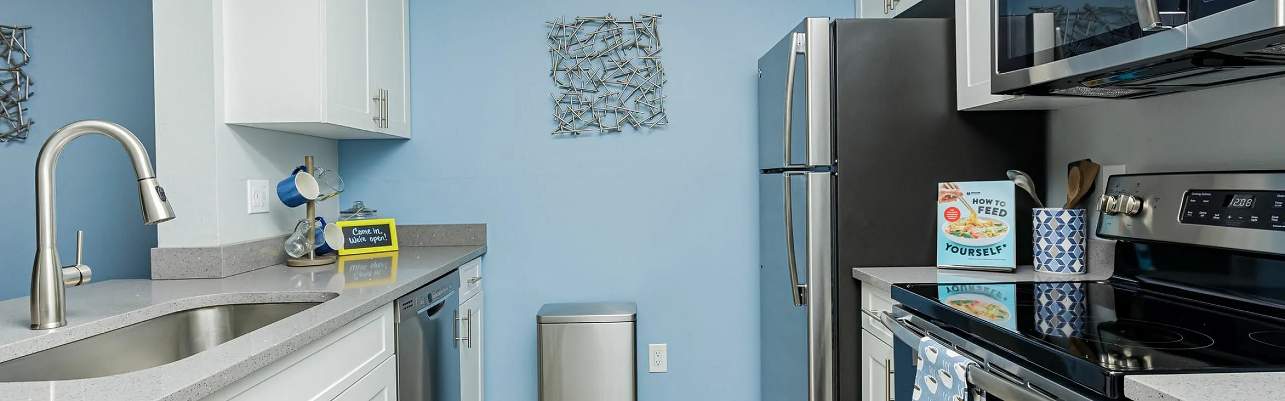 Modern kitchen with sleek stainless steel appliances, elegant white cabinetry, and stylish blue accent wall. Spacious and contemporary design perfect for culinary adventures.