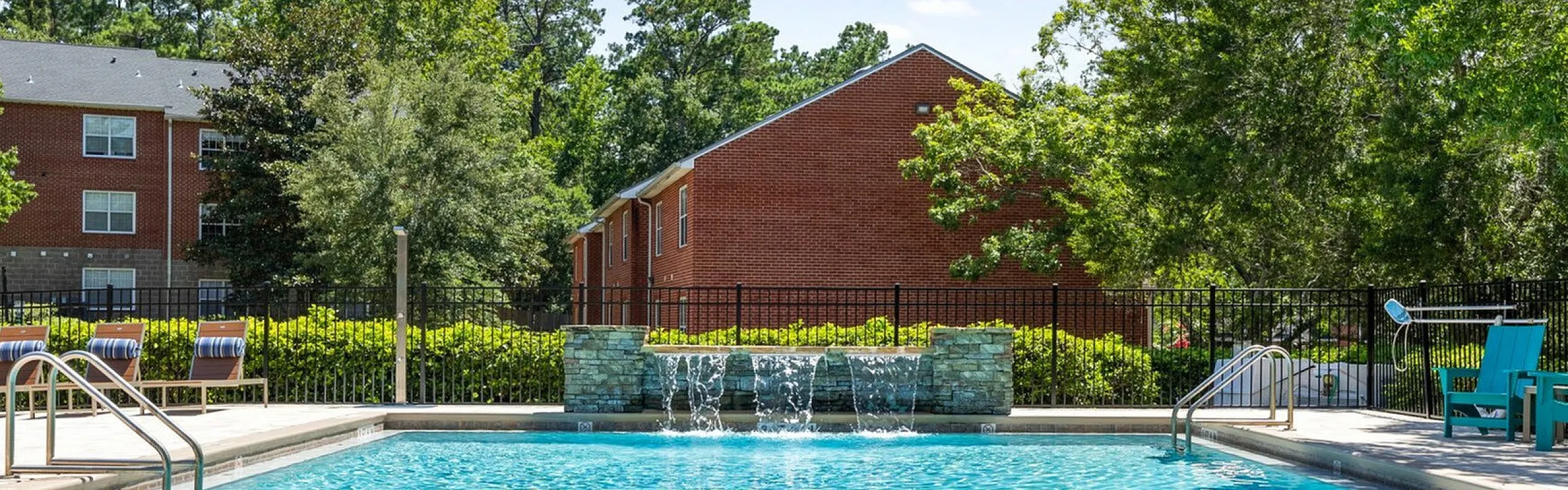 Inviting outdoor pool with cascading water features, surrounded by lush greenery, offering a serene and relaxing environment.