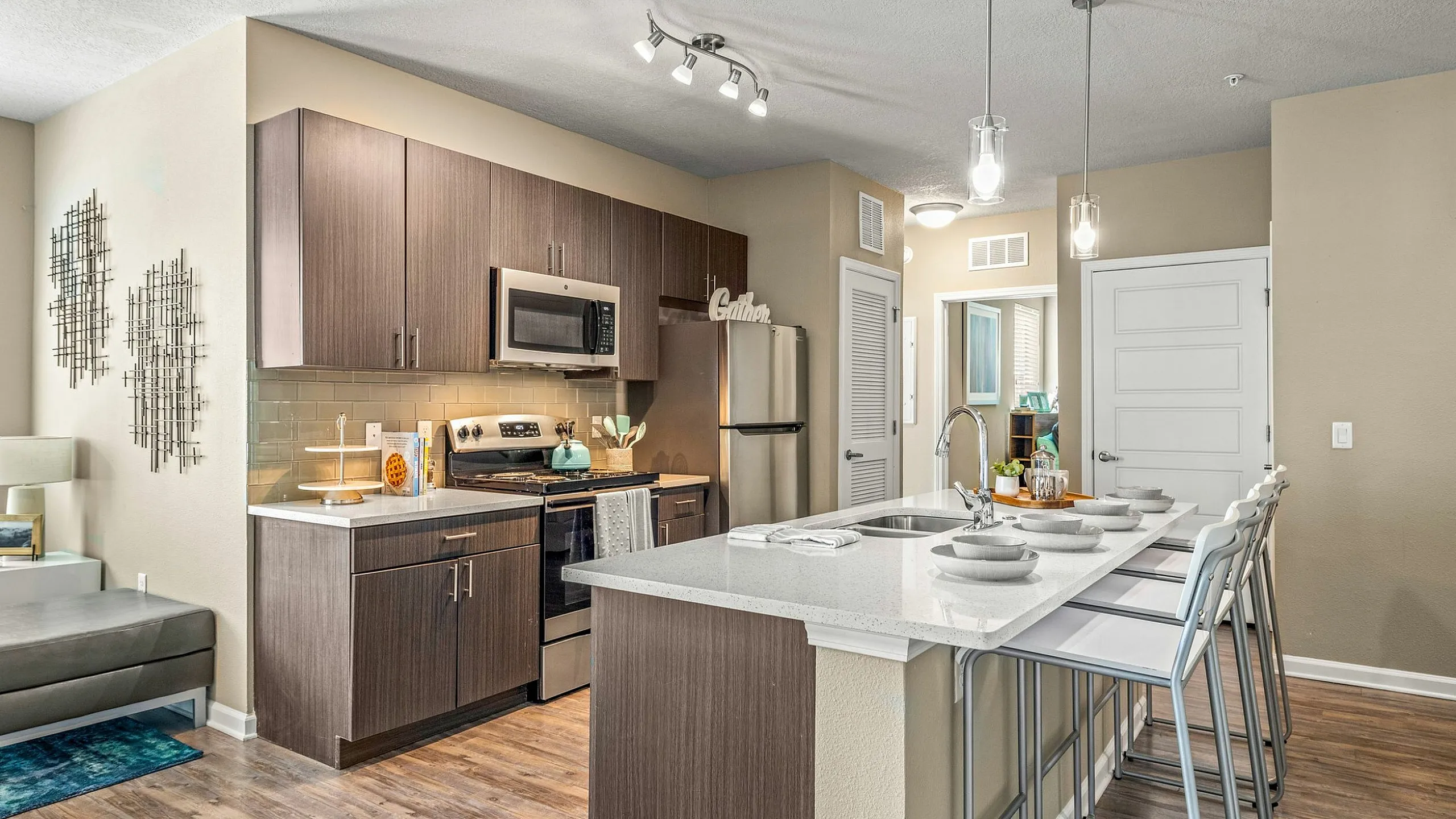 Modern apartment kitchen with elegant cabinetry, stainless steel appliances, and a chic breakfast bar featuring stylish bar stools.