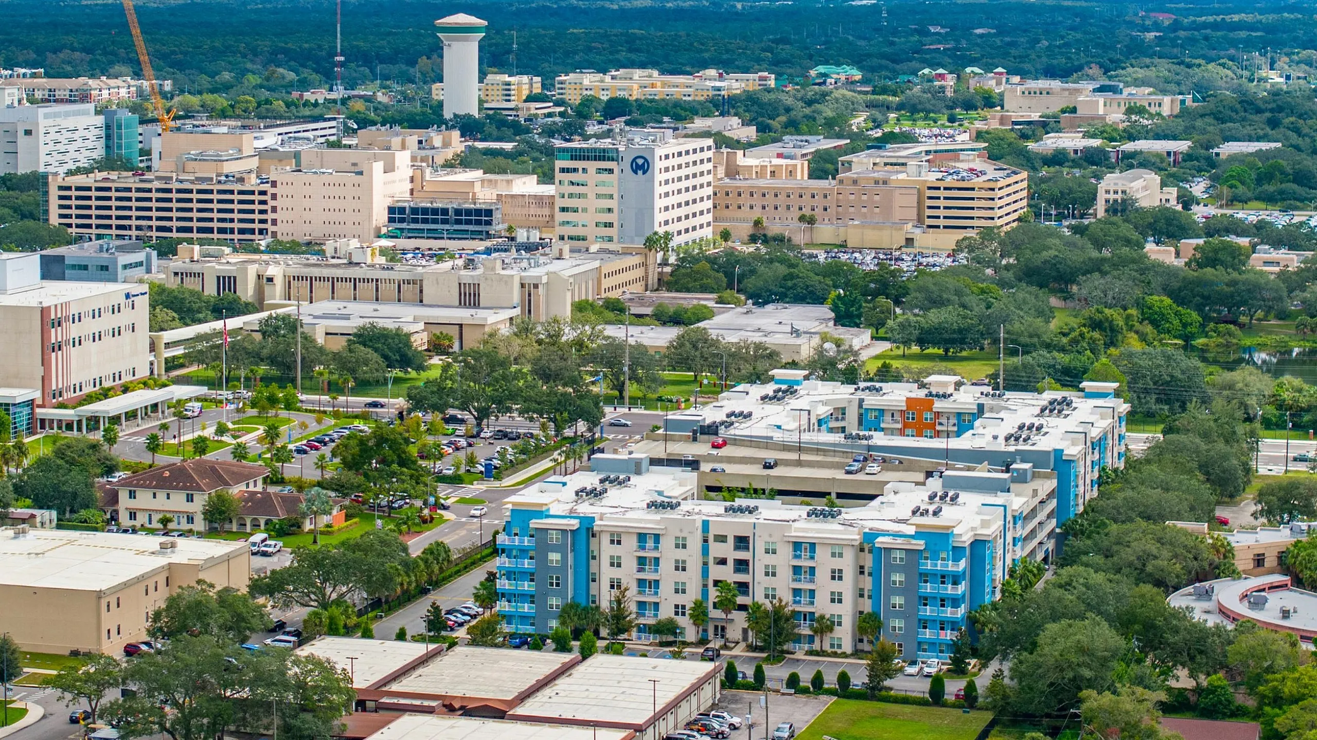 Vibrant urban skyline featuring modern apartment complexes surrounded by lush greenery and a bustling cityscape.