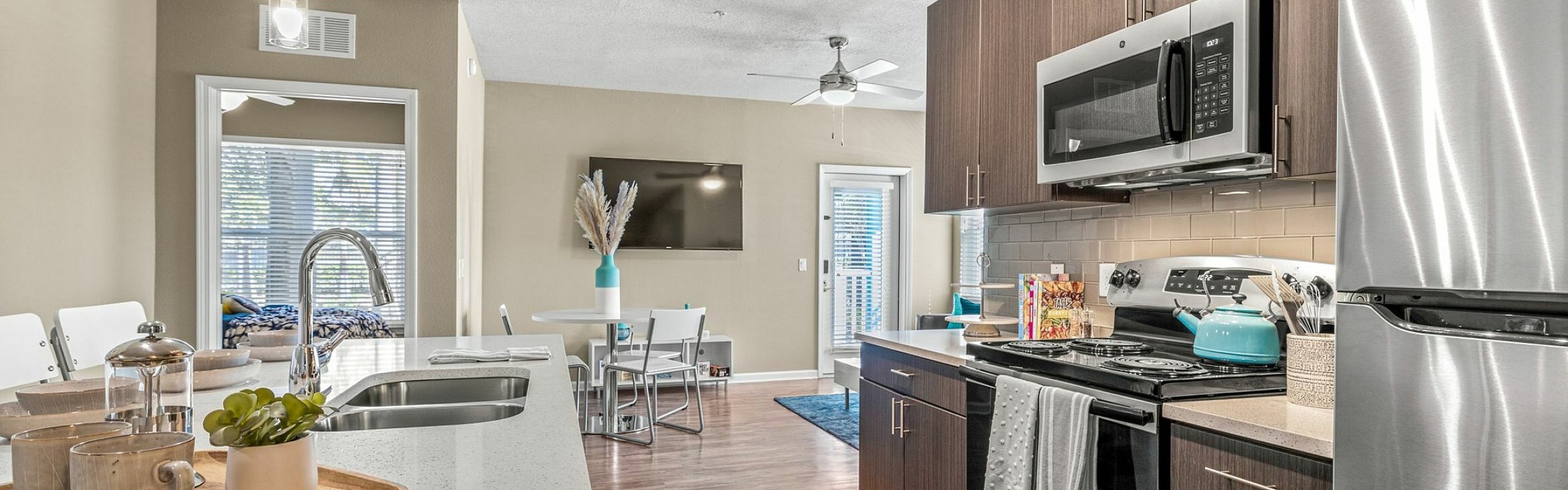 Modern kitchen with sleek stainless steel appliances, spacious countertops, and elegant wood cabinets leading into a cozy dining area.