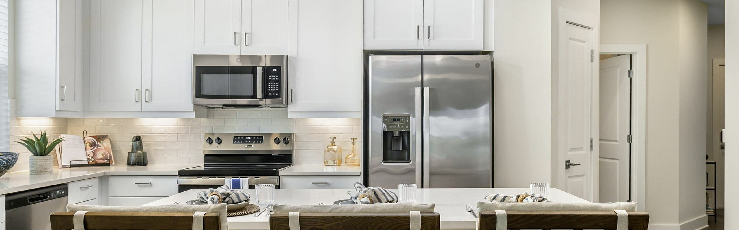 Modern kitchen with sleek white cabinetry, stainless steel appliances, and an inviting breakfast bar with stylish stools.