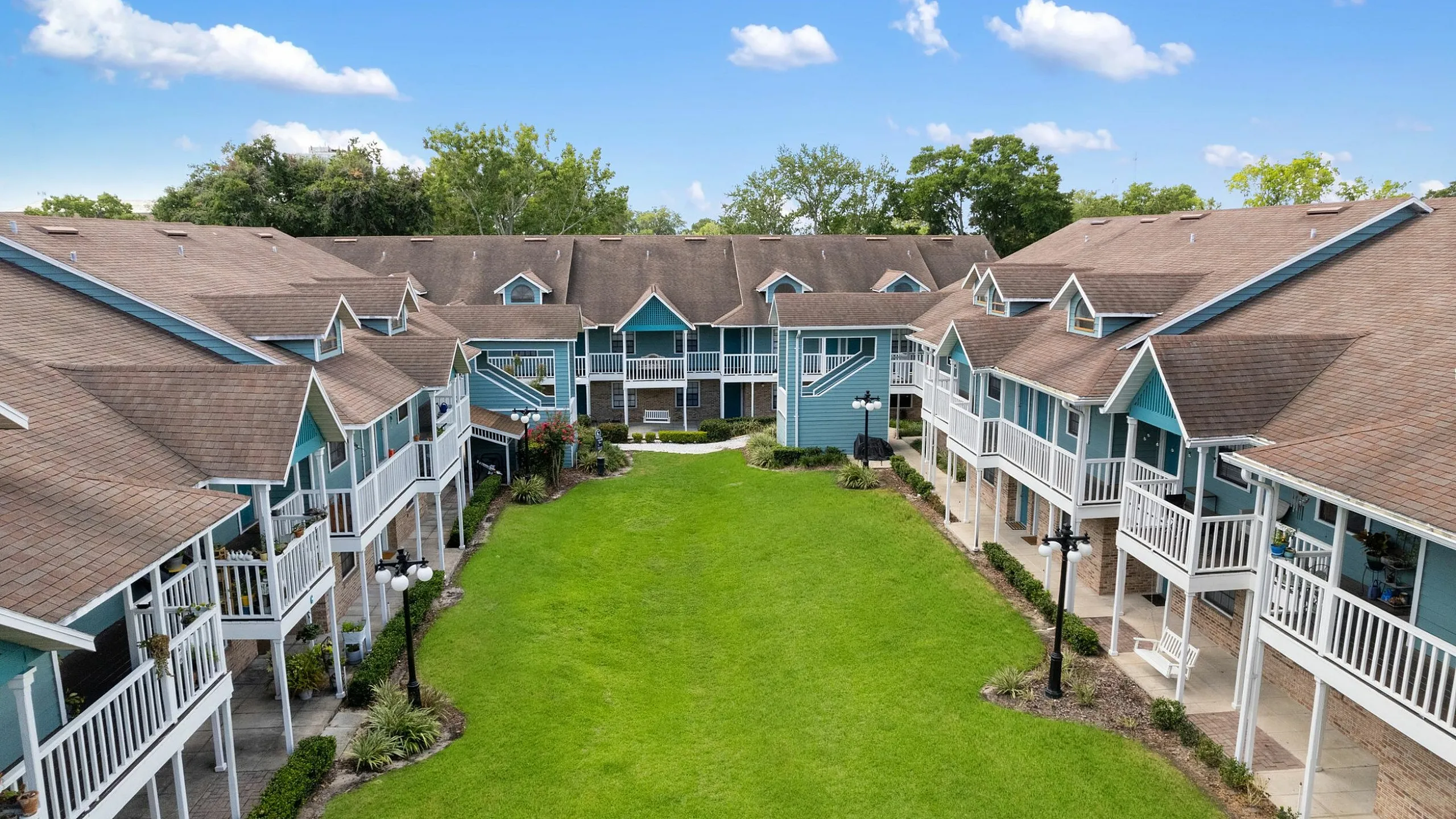 Charming community of townhouses featuring a lush central green courtyard and welcoming porches, ideal for relaxed living.