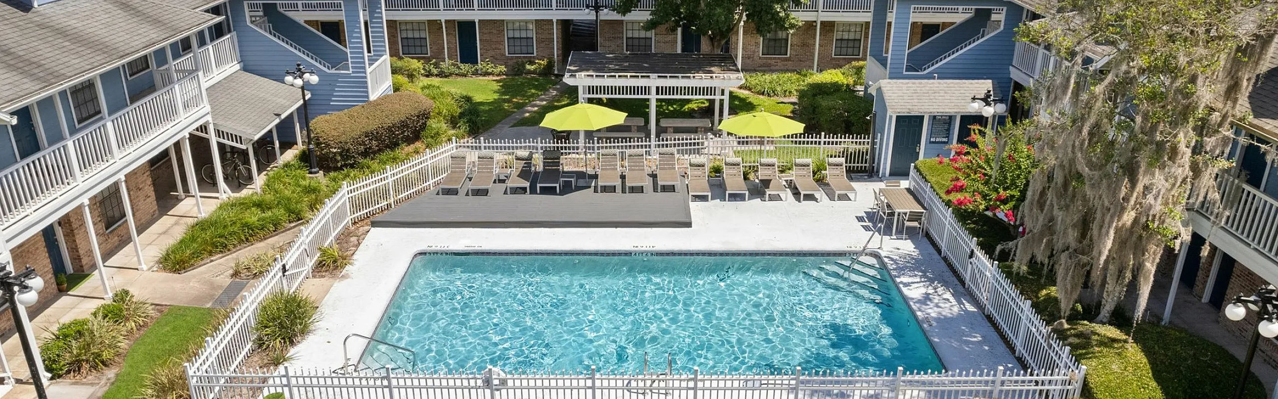 Charming residential complex showcasing a serene pool area, vibrant landscaping, and inviting balconies for relaxed outdoor living.