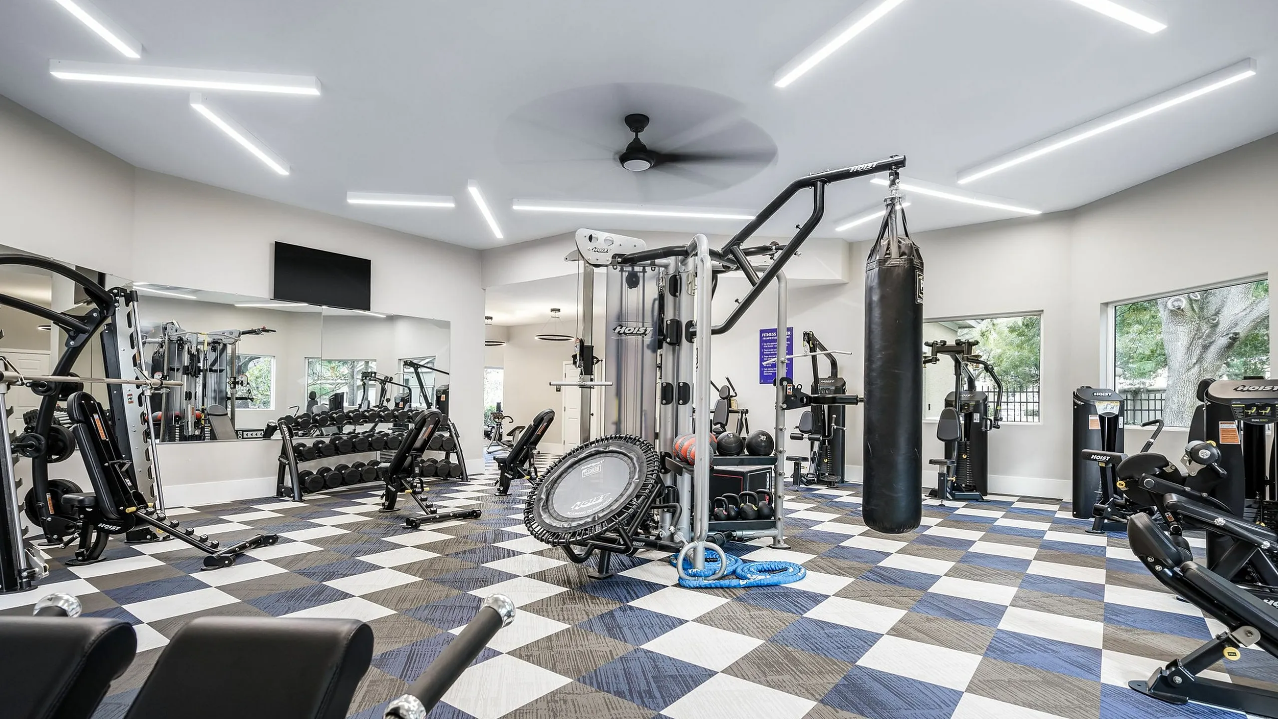 Modern gym with state-of-the-art fitness equipment, checkered flooring, and large mirrors for an energizing workout experience.