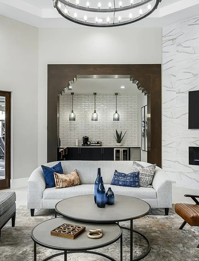 Modern living room with chic decor featuring plush seating, stylish light fixture, and elegant fireplace under a wall-mounted TV, creating a cozy ambiance.