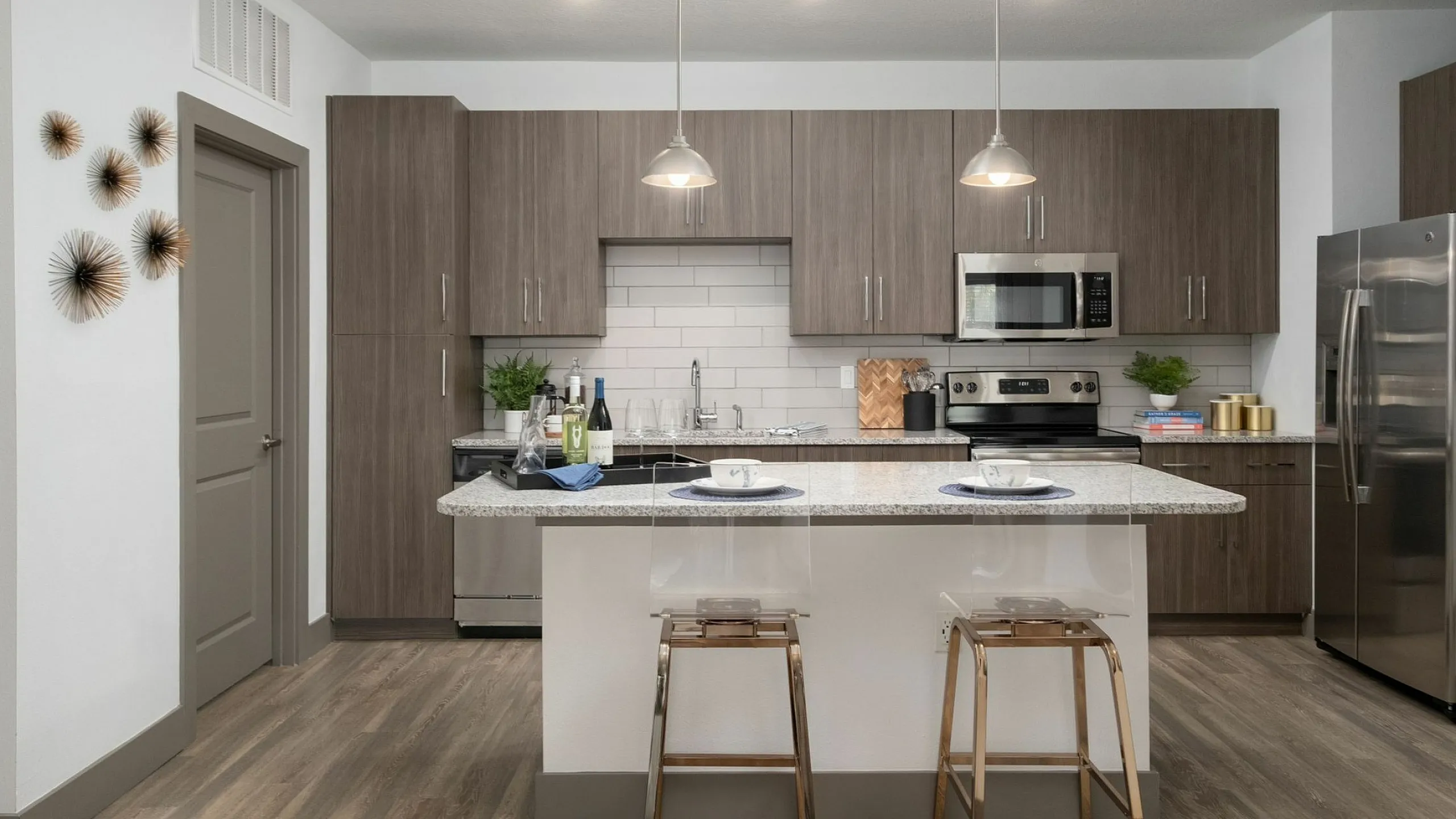 Modern kitchen with sleek cabinetry, stainless steel appliances, elegant pendant lighting, and a stylish breakfast bar with seating.