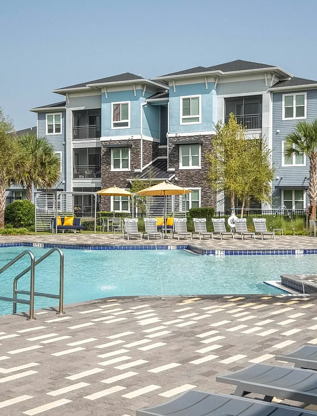 Luxurious apartment with a sparkling outdoor pool, surrounded by palm trees and modern sun loungers, perfect for relaxation.
