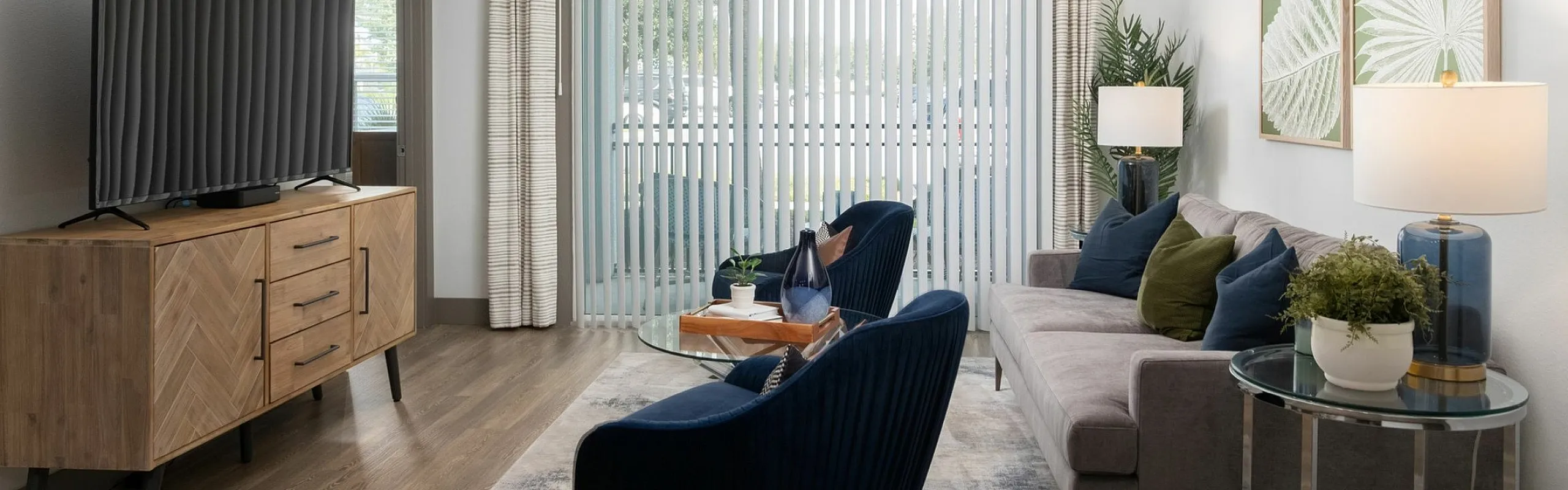 Modern living room with plush seating, large TV, elegant decor, and abundant natural light from sliding glass doors.