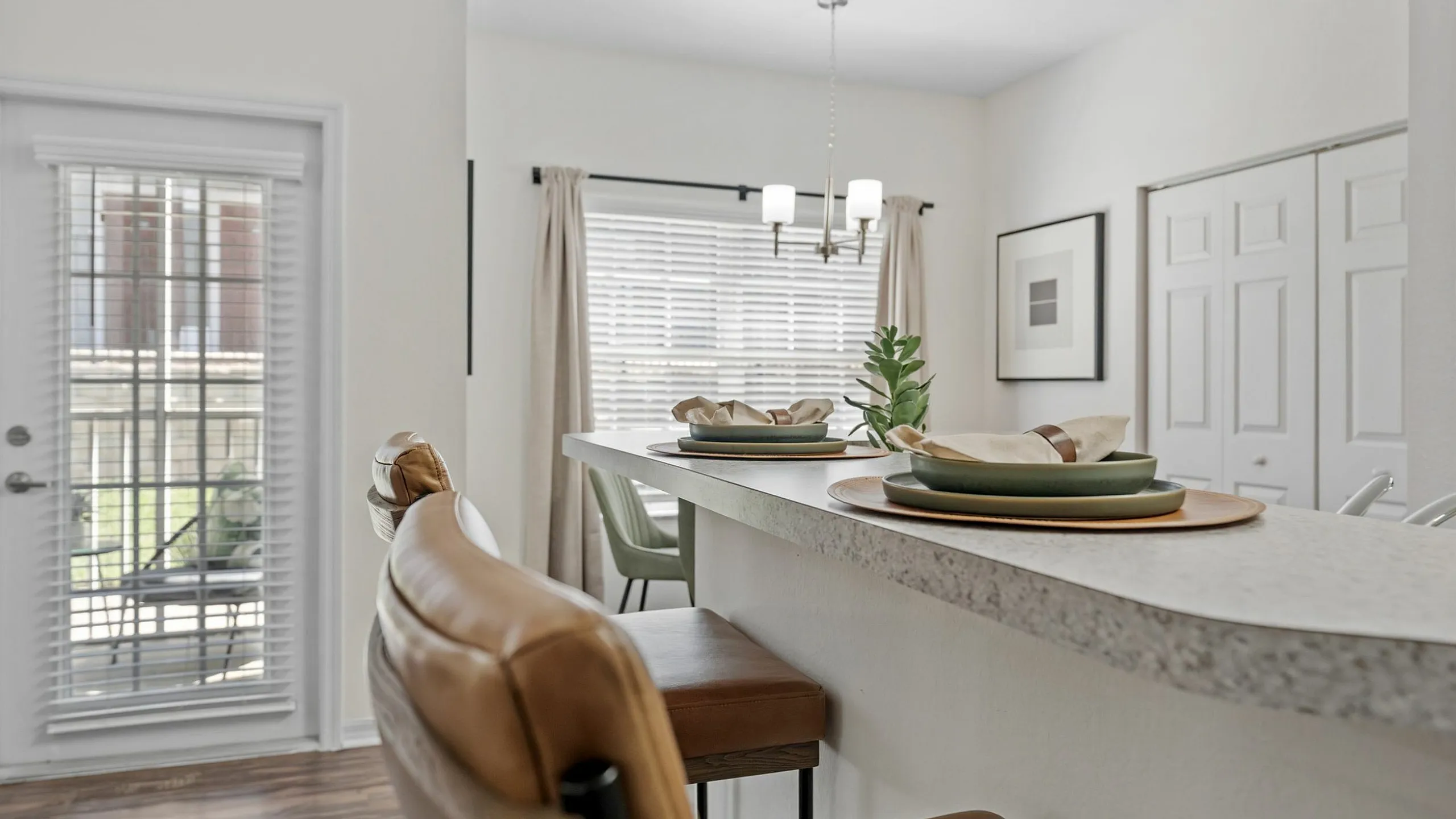 Bright apartment dining area with elegant bar seating, chic decor, and a view of the outdoor patio through stylish French doors.