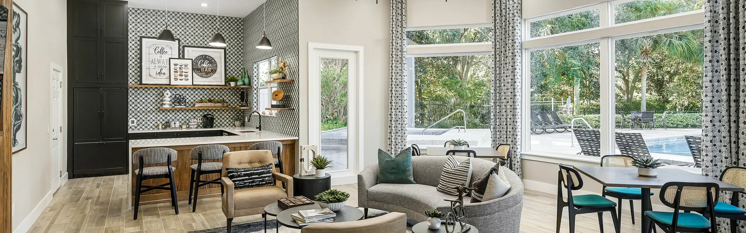 Luxurious apartment lounge with modern decor, featuring elegant chandeliers, cozy seating, and large windows overlooking a serene pool area.