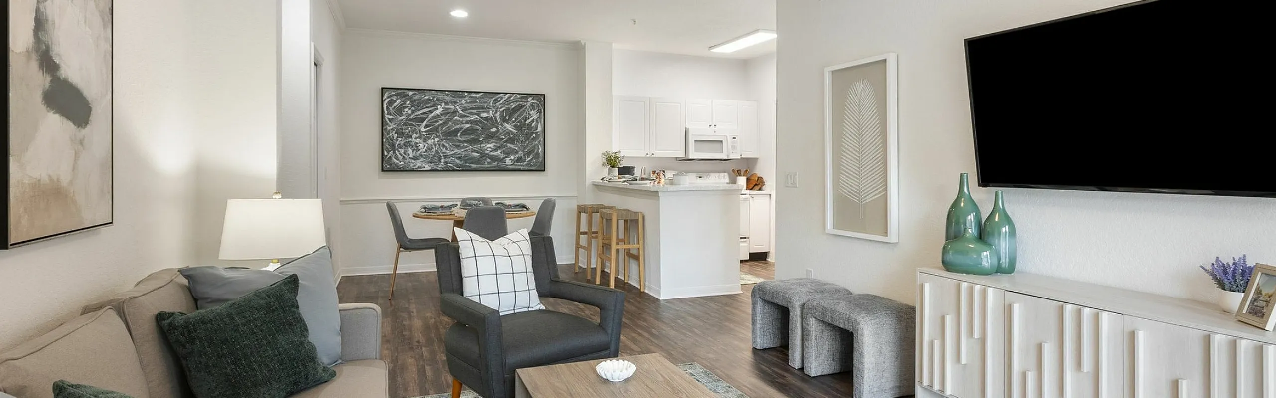 Bright and welcoming living area featuring modern decor, sleek furniture, and an open-concept design with a stylish kitchenette and dining space.