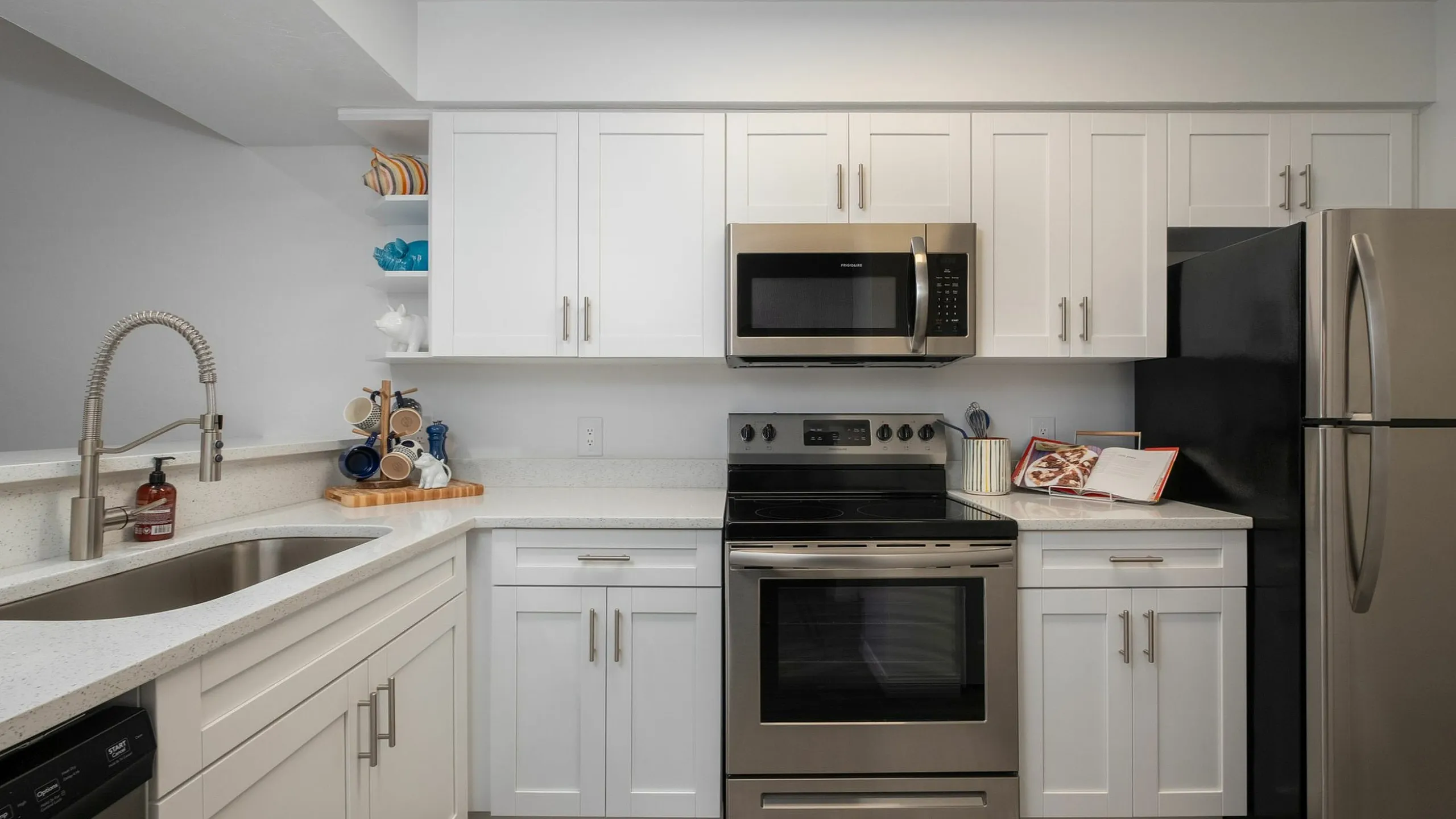 Modern kitchen with sleek stainless steel appliances, pristine white cabinetry, and elegant countertops.