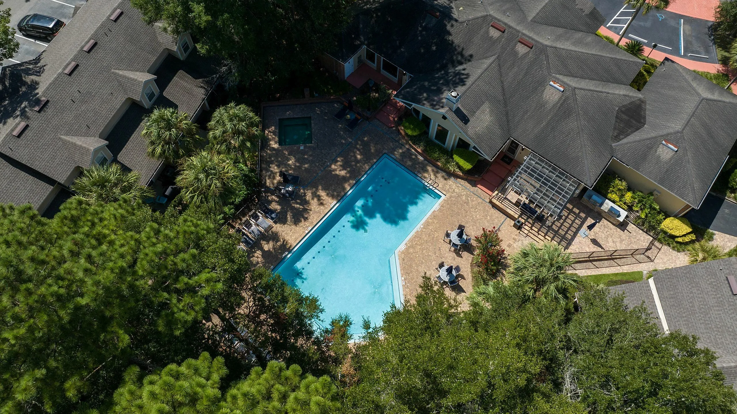 Aerial view of a luxurious apartment complex featuring a sparkling swimming pool, surrounded by lush greenery and modern buildings, perfect for relaxation and leisure.