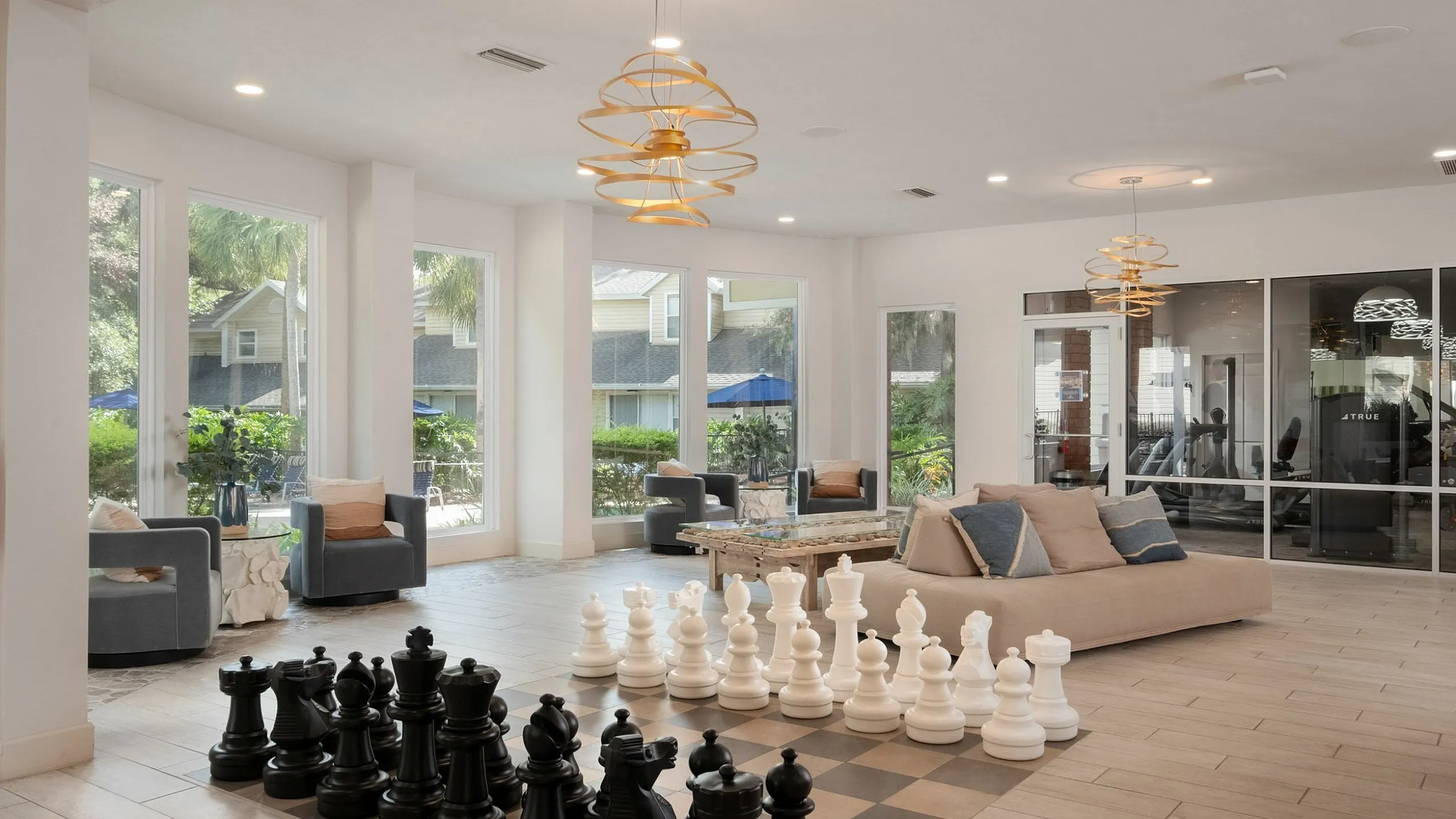 Modern living space with large windows, cozy seating, and an oversized chess set offering a unique blend of style and comfort.