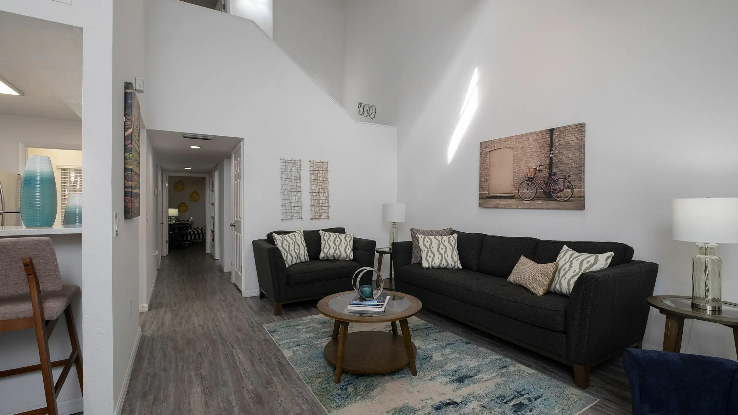 Inviting living room with high ceilings, modern gray sofas, and elegant decor in a bright apartment.