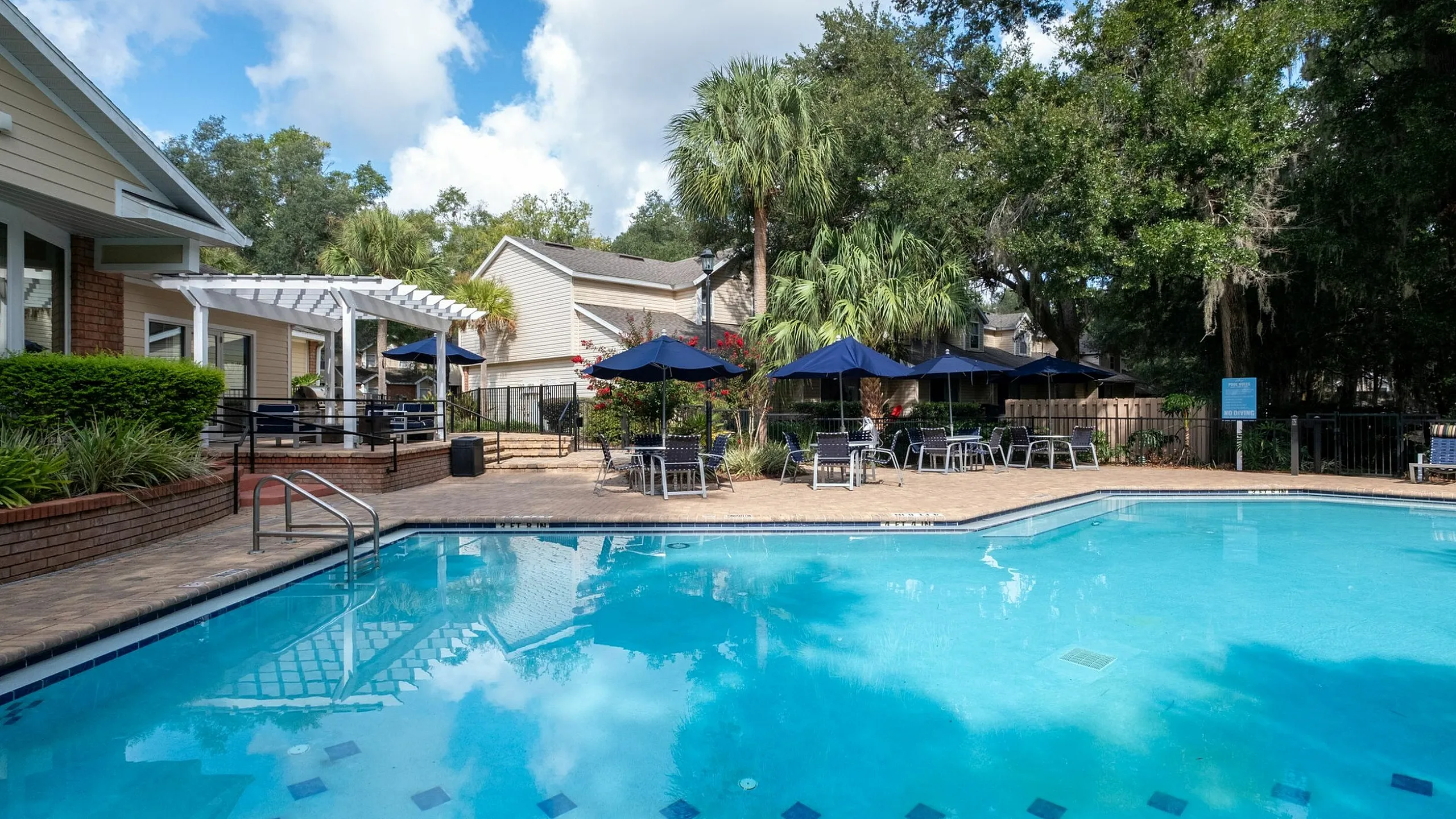 Charming outdoor pool area with inviting lounge chairs and vibrant landscaping under a bright blue sky.