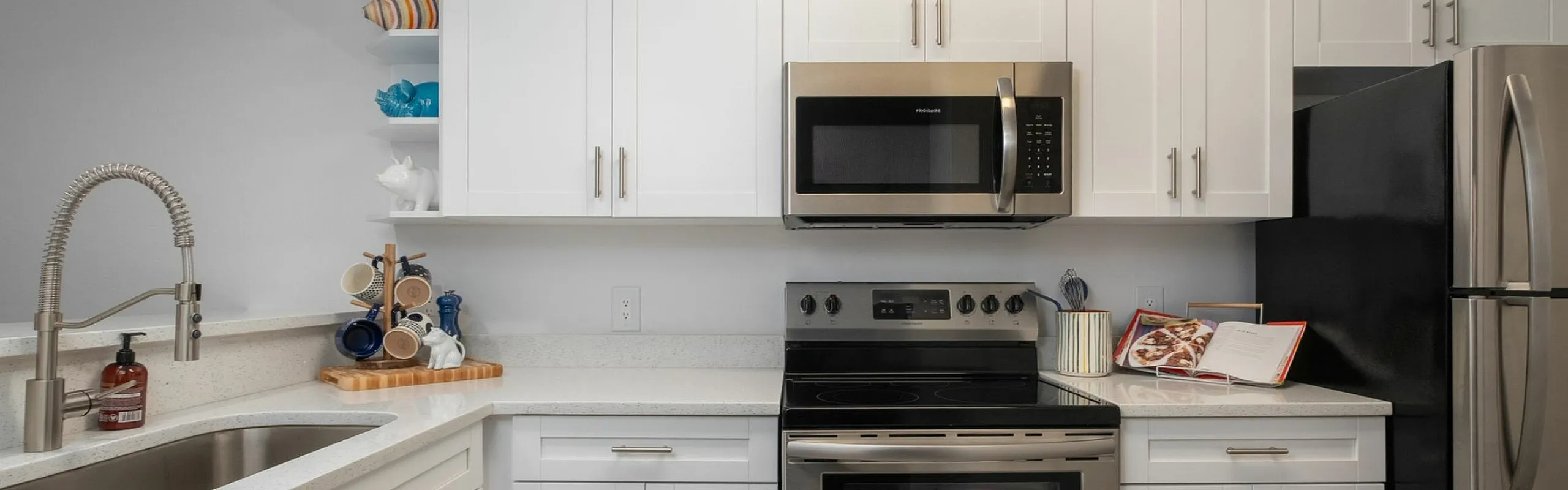 Modern kitchen with sleek stainless steel appliances, elegant white cabinetry, and stylish countertops offering a contemporary and inviting cooking space.