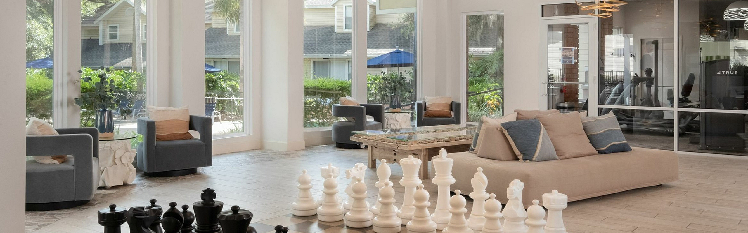 Inviting apartment clubhouse with elegant modern design, featuring a cozy seating area and oversized chess set for leisure.
