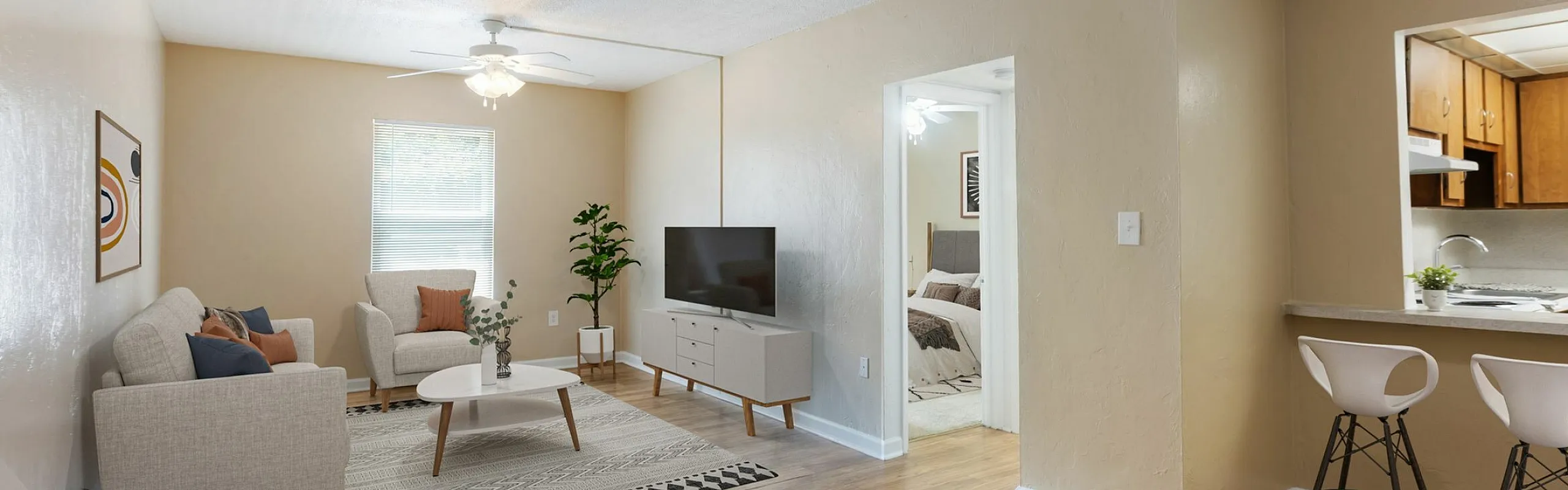 Inviting apartment interior with a cozy living room featuring modern furniture, hardwood floors, and an open kitchen with bar seating.