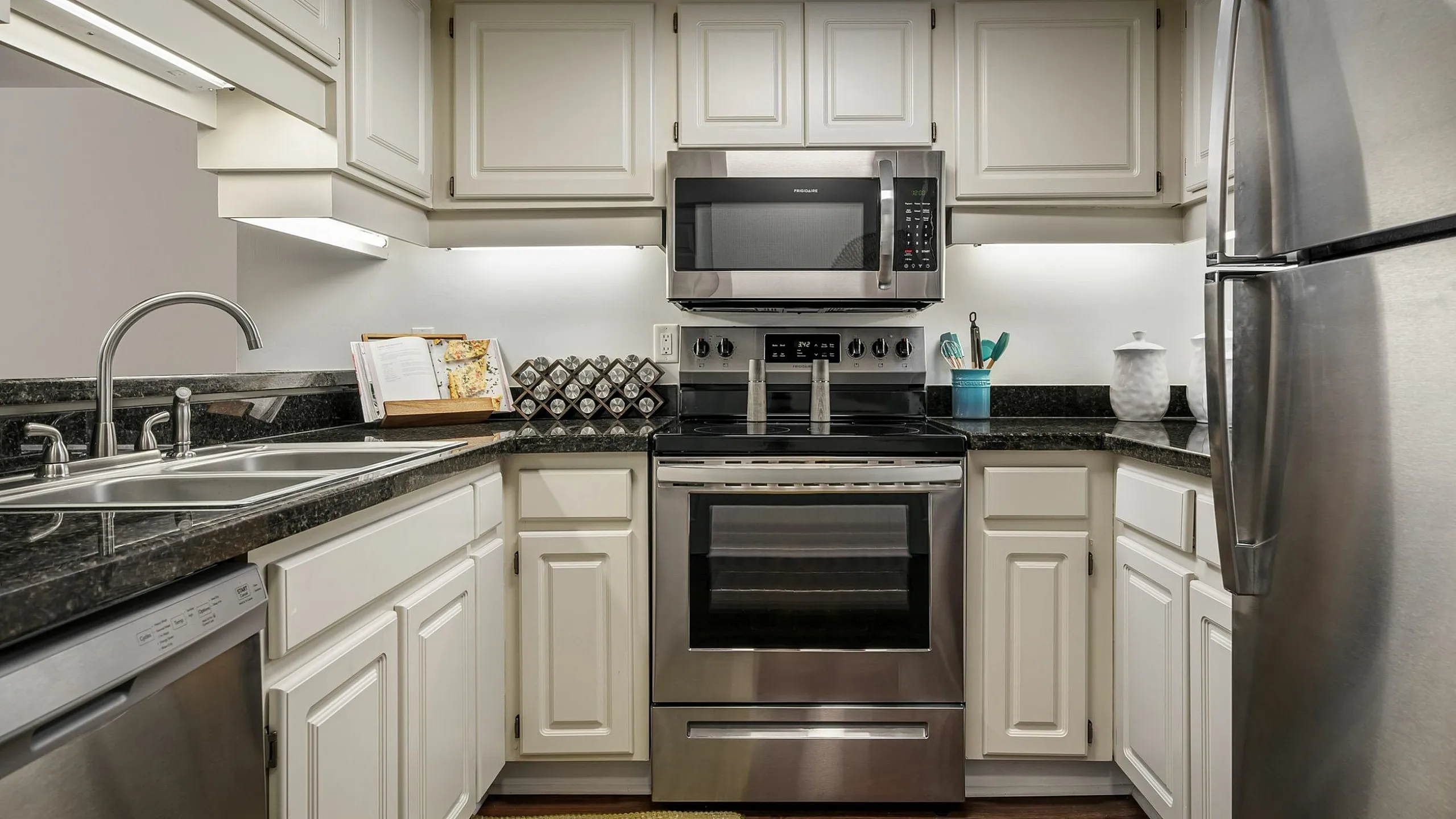 Modern kitchen with sleek stainless steel appliances, elegant white cabinetry, and granite countertops, creating a stylish and functional cooking space.
