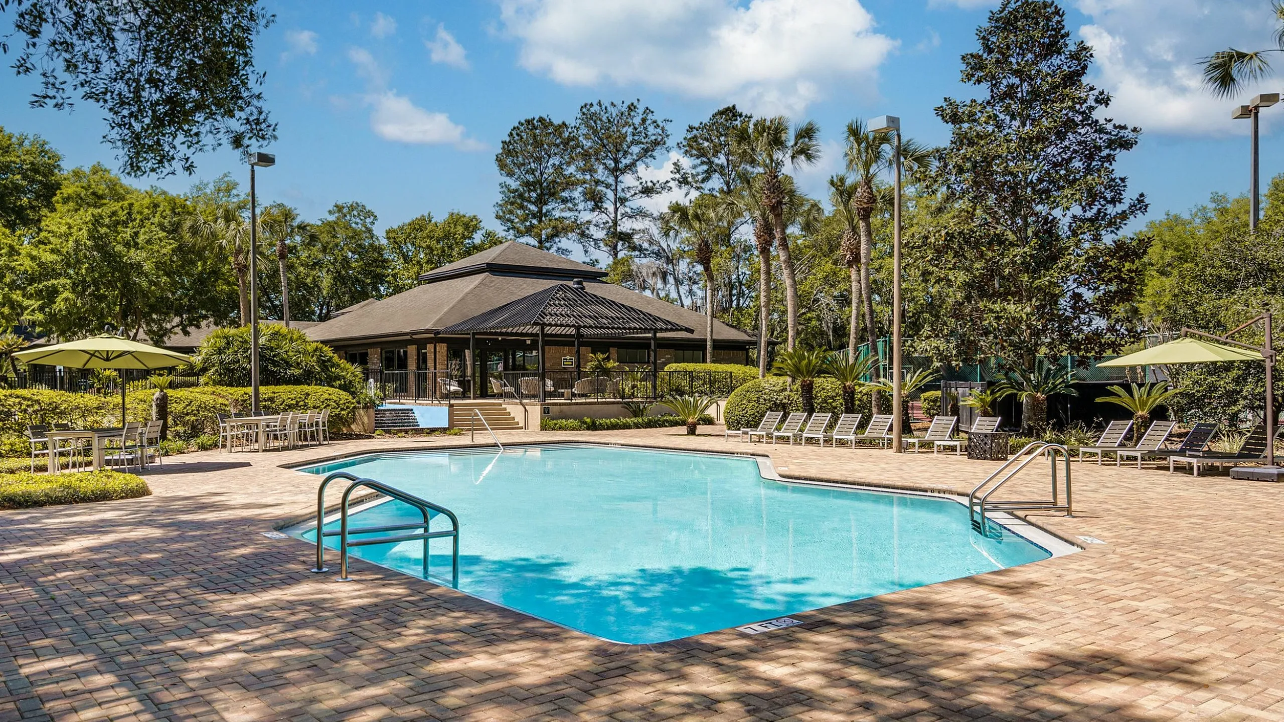 Inviting outdoor pool area surrounded by lush greenery and sun loungers, perfect for relaxation and leisure.