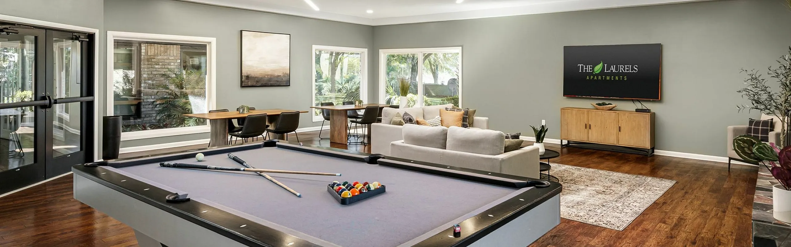 Luxurious communal space with a modern pool table, elegant seating area, and chic dining setup at The Laurels Apartments.