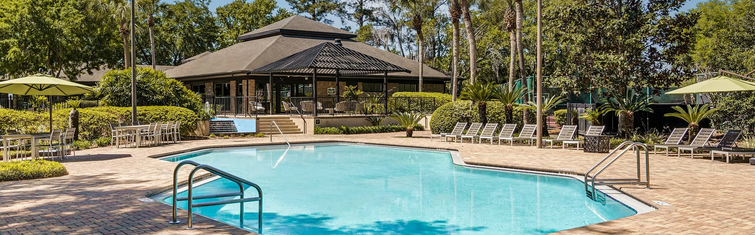 Inviting outdoor pool area surrounded by lush greenery and comfortable sun loungers, perfect for relaxation.
