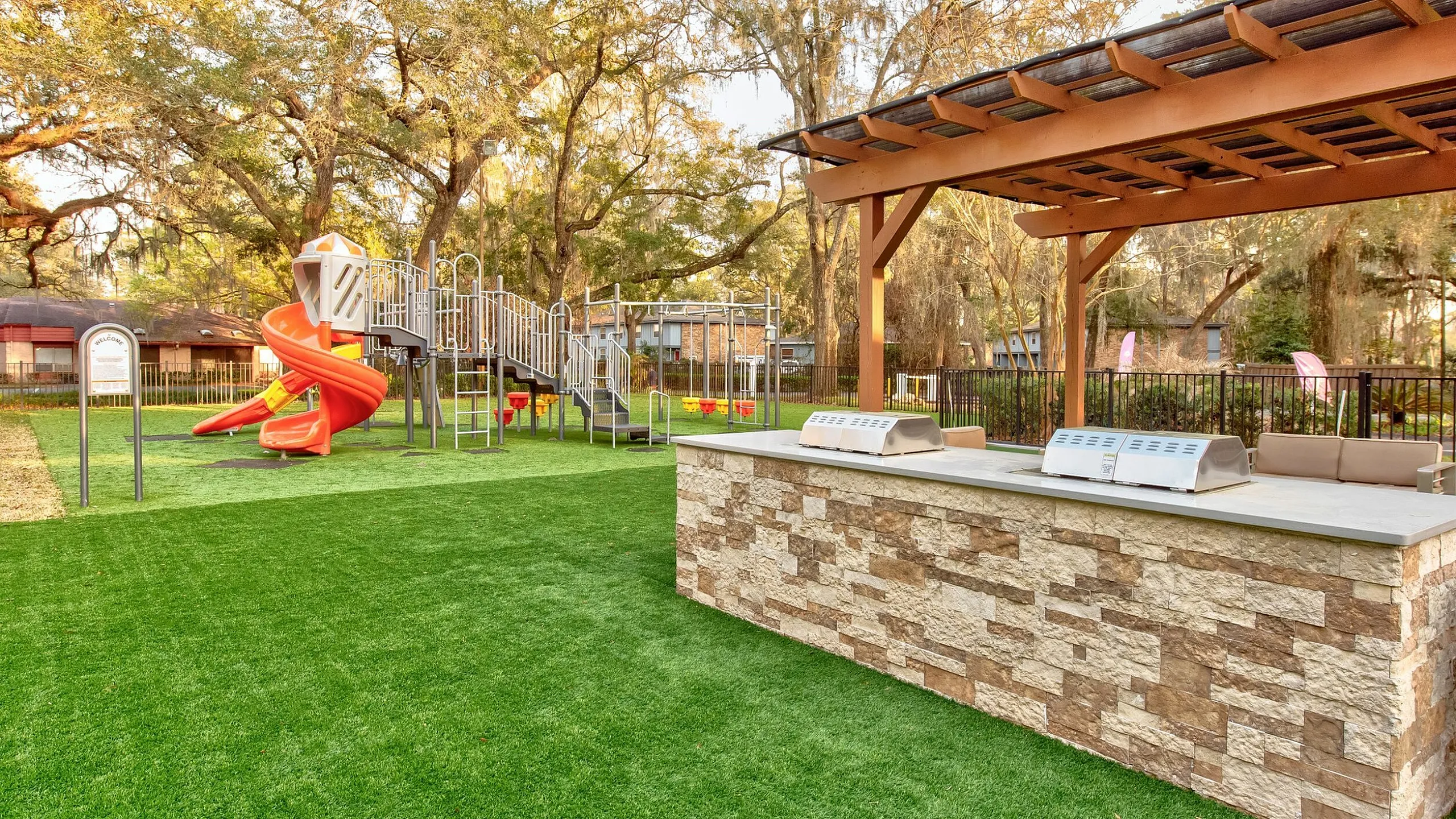 Inviting outdoor space with a modern barbecue area and vibrant playground surrounded by lush greenery.