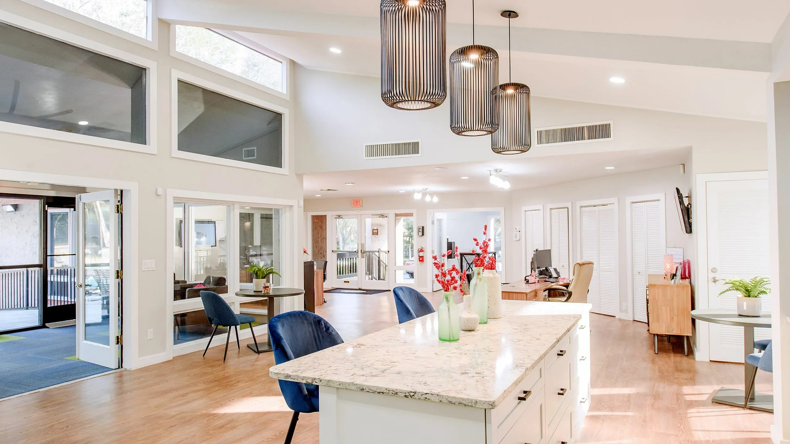 Bright and modern open-concept living space with high ceilings, large windows, and elegant pendant lighting, featuring a stylish kitchen island and comfortable seating area.