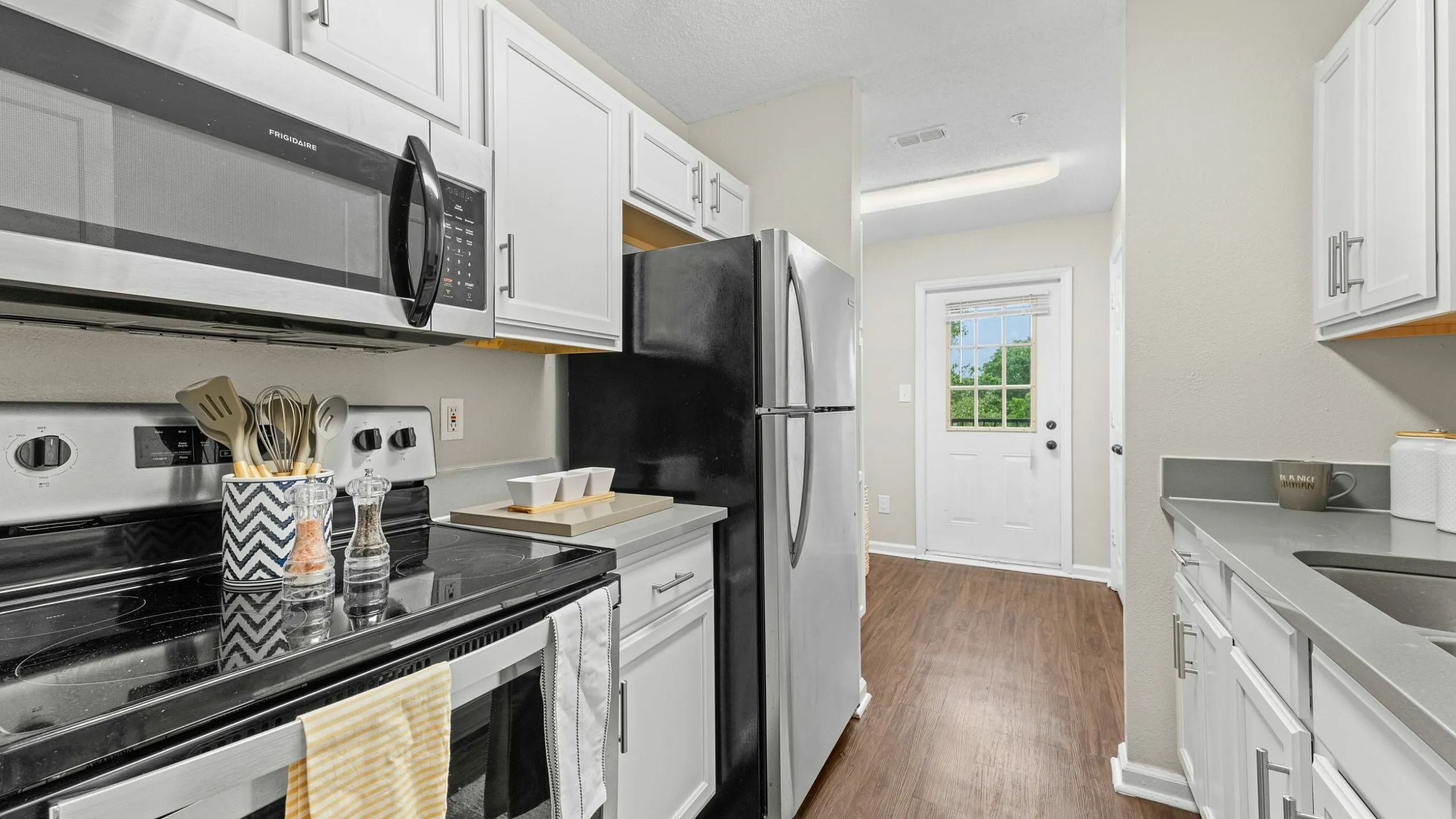 Bright, modern kitchen with sleek stainless steel appliances, elegant cabinetry, and warm wood floors, perfect for culinary creativity.