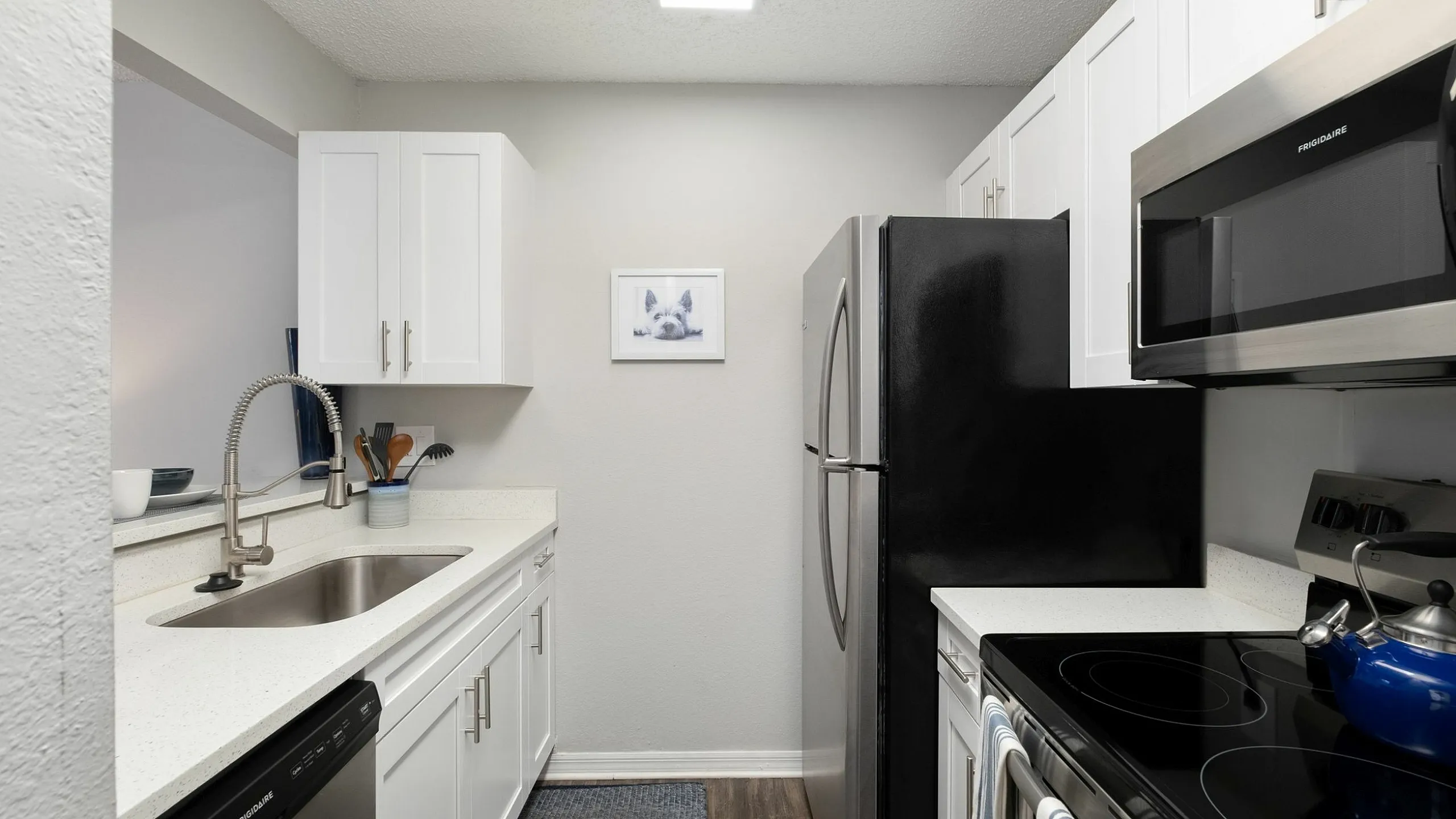 Modern kitchen with sleek stainless steel appliances, bright white cabinets, and elegant countertops, featuring a cozy and inviting layout.