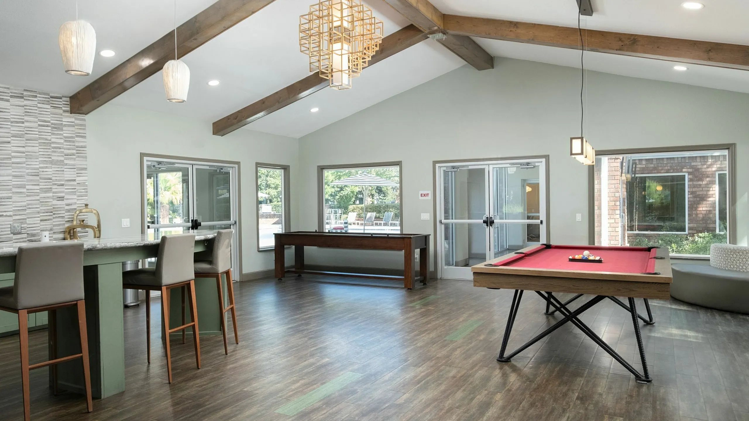 Inviting recreational area with a modern pool table, elegant bar seating, and chic lighting, ideal for social gatherings.
