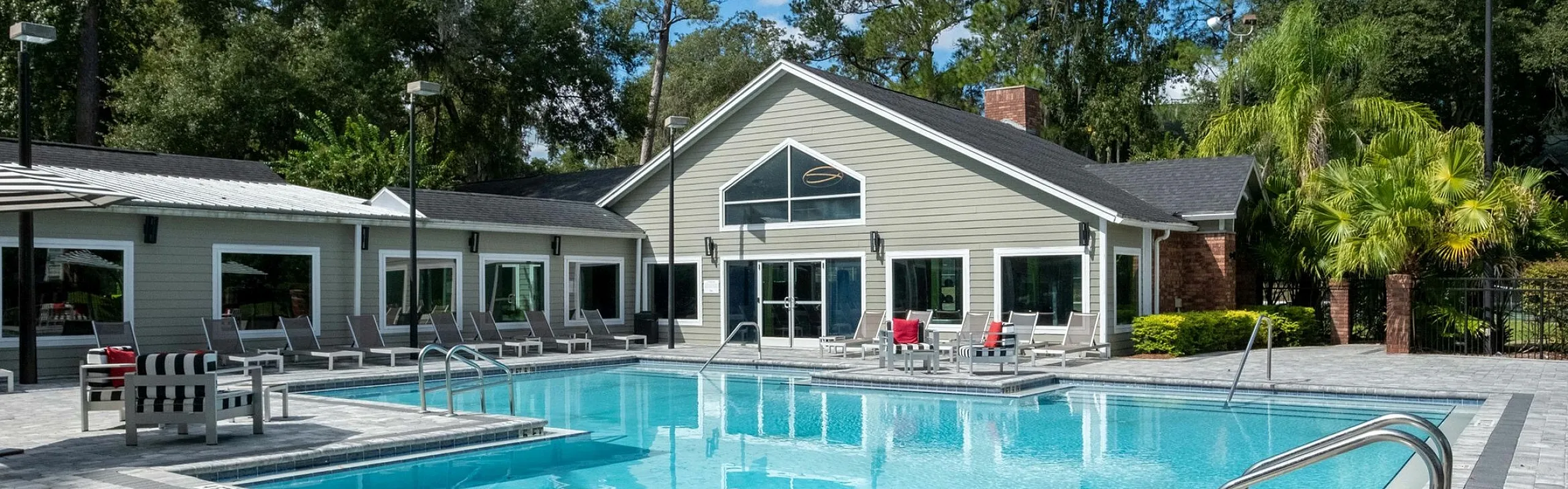 Inviting pool area with modern lounge chairs and lush greenery, perfect for relaxation and leisure.