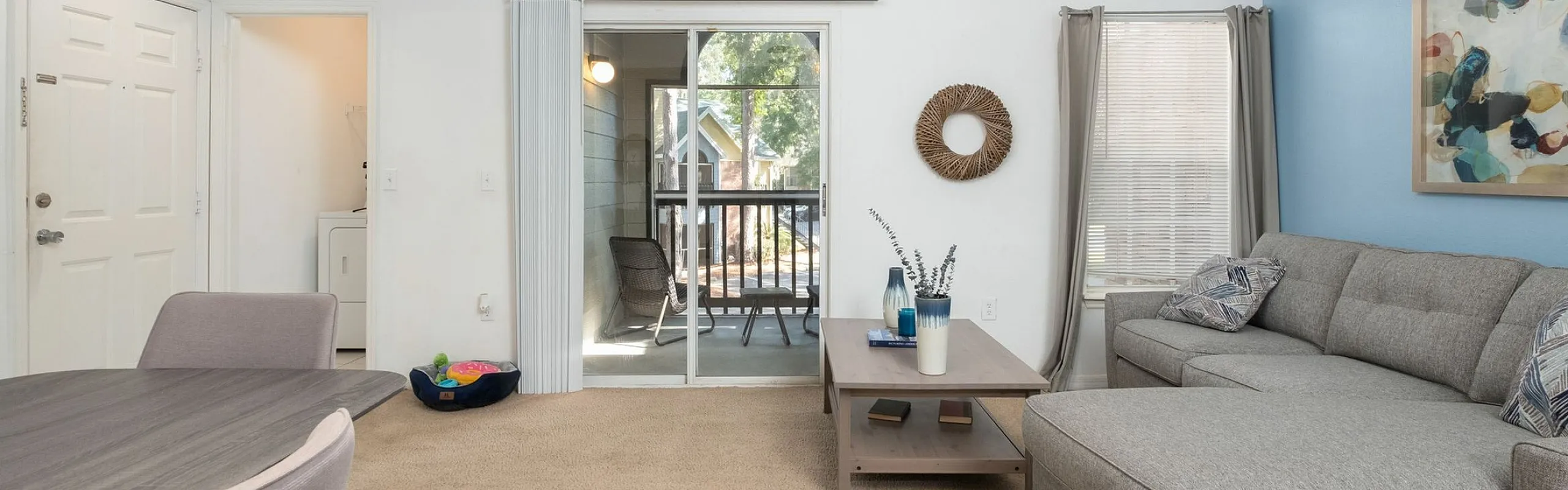 Bright living room with modern gray sectional, elegant decor, and access to a charming balcony.