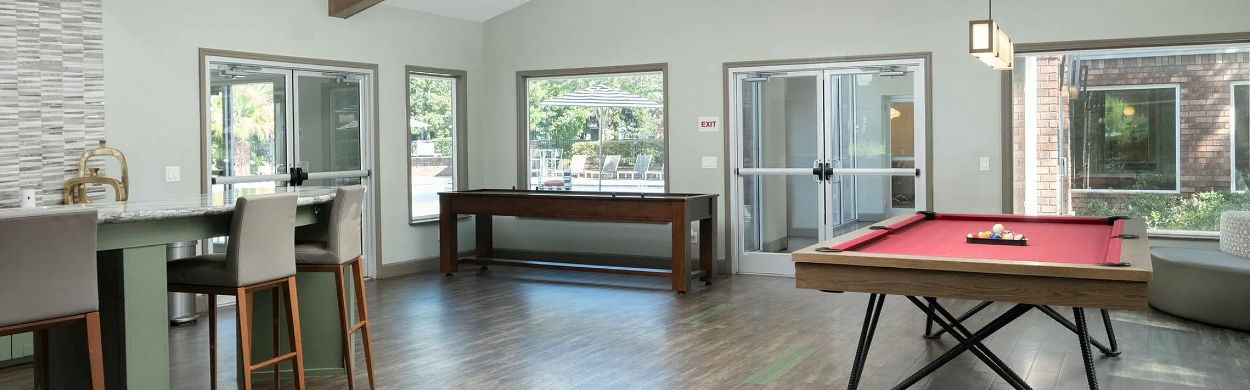 Stylish community lounge featuring elegant wood beam ceilings, a contemporary bar area, and a vibrant pool table for entertainment.