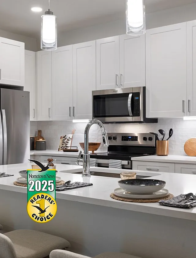 Modern kitchen with sleek white cabinets, stainless steel appliances, and a stylish island with seating, highlighting a bright and functional space.
