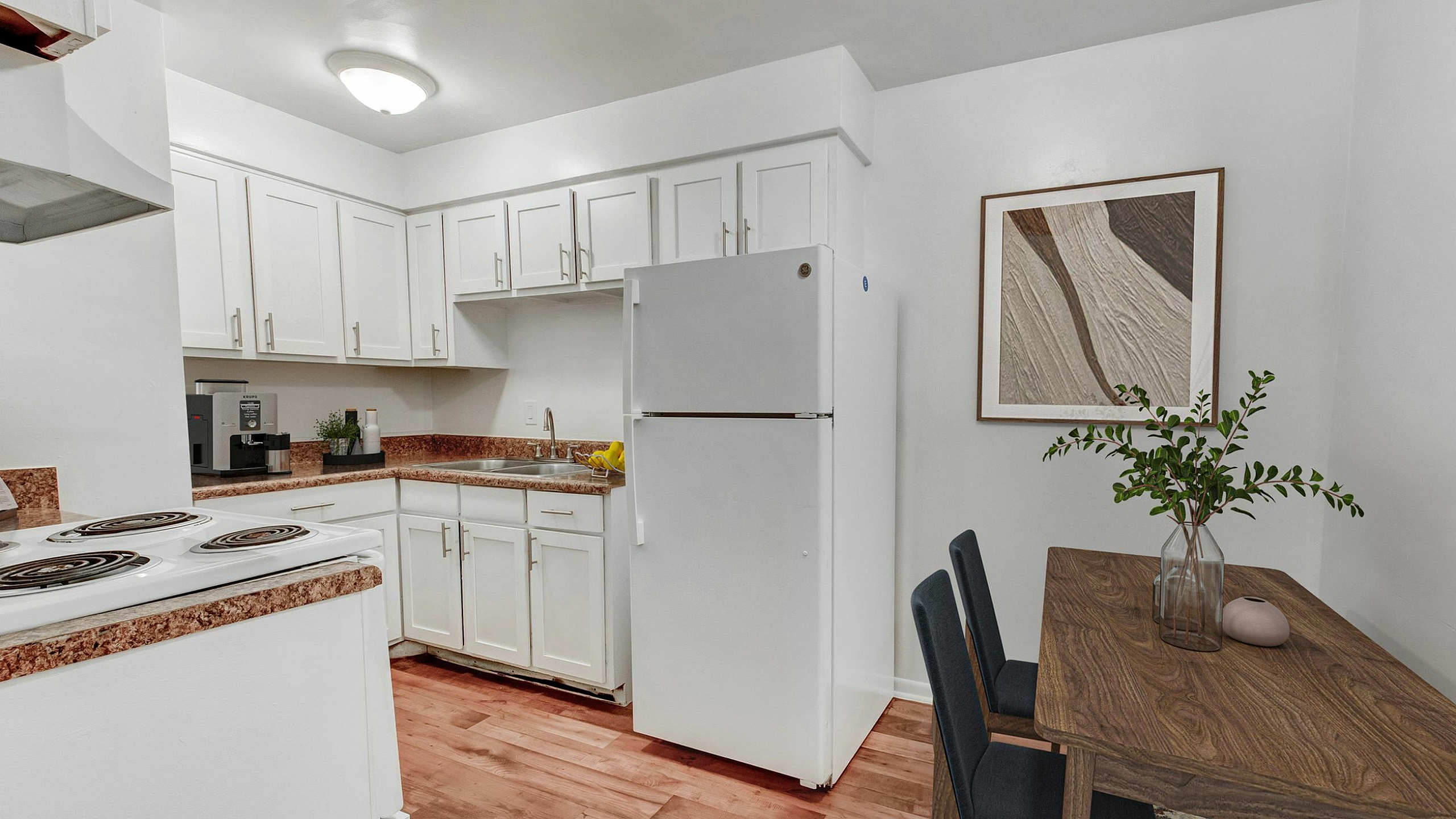 Charming kitchen with sleek white cabinetry, modern appliances, and a cozy dining area perfect for intimate gatherings.