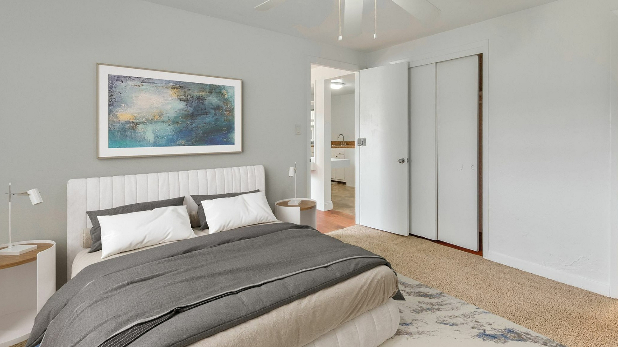 Elegant bedroom with a cozy bed, stylish artwork, and a serene color palette, showcasing an adjoining modern bathroom and ample closet space.