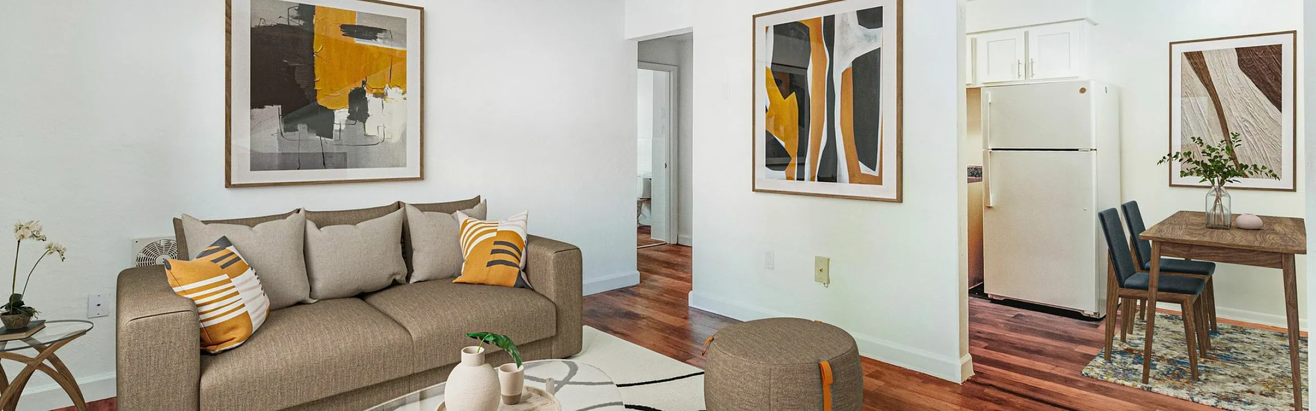 Chic living room with modern decor, featuring a cozy sofa, abstract art pieces, and an inviting kitchen nook in a bright, open layout.