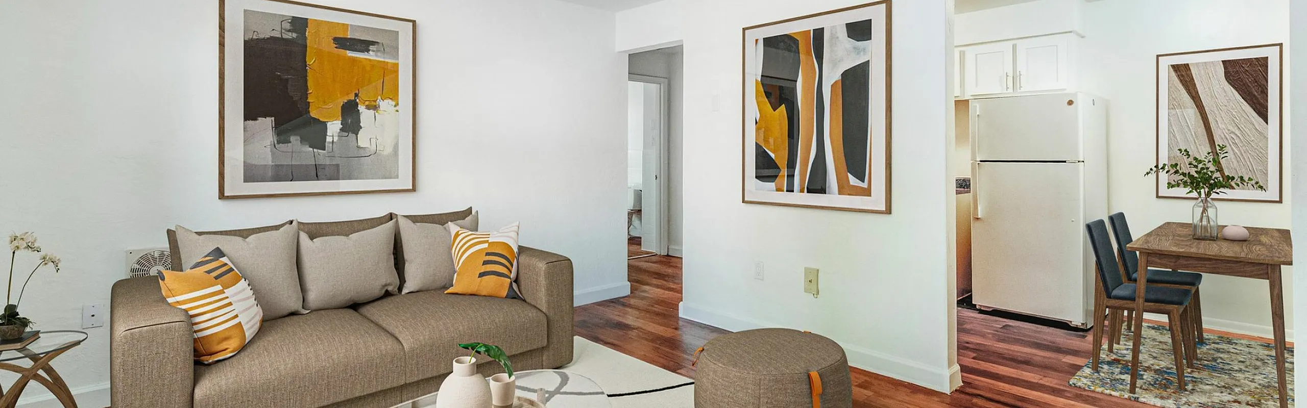Contemporary living room with a cozy beige sofa, colorful abstract art, and an inviting open-concept kitchen-dining area.