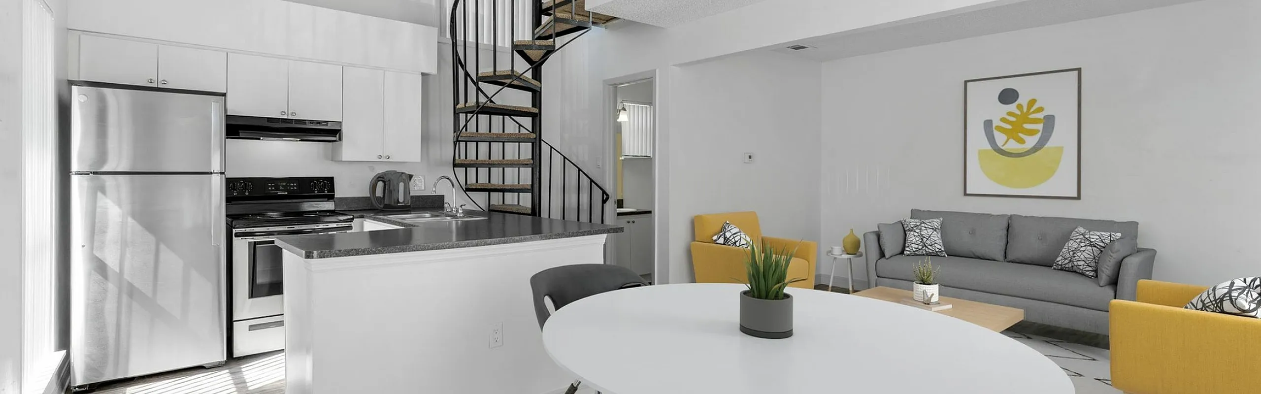 Modern open-plan living area with a sleek kitchen, stylish spiral staircase, and chic furnishings in a bright and airy space.