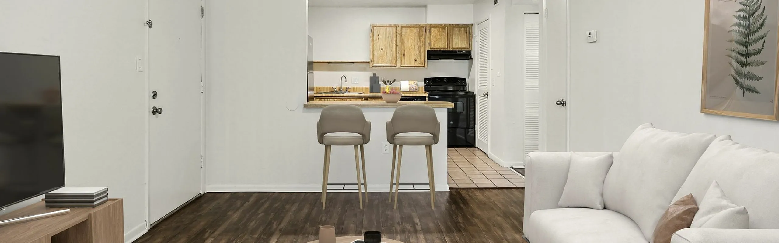 Modern open-concept living area with a cozy couch, sleek TV setup, and stylish kitchen breakfast bar featuring two stools.